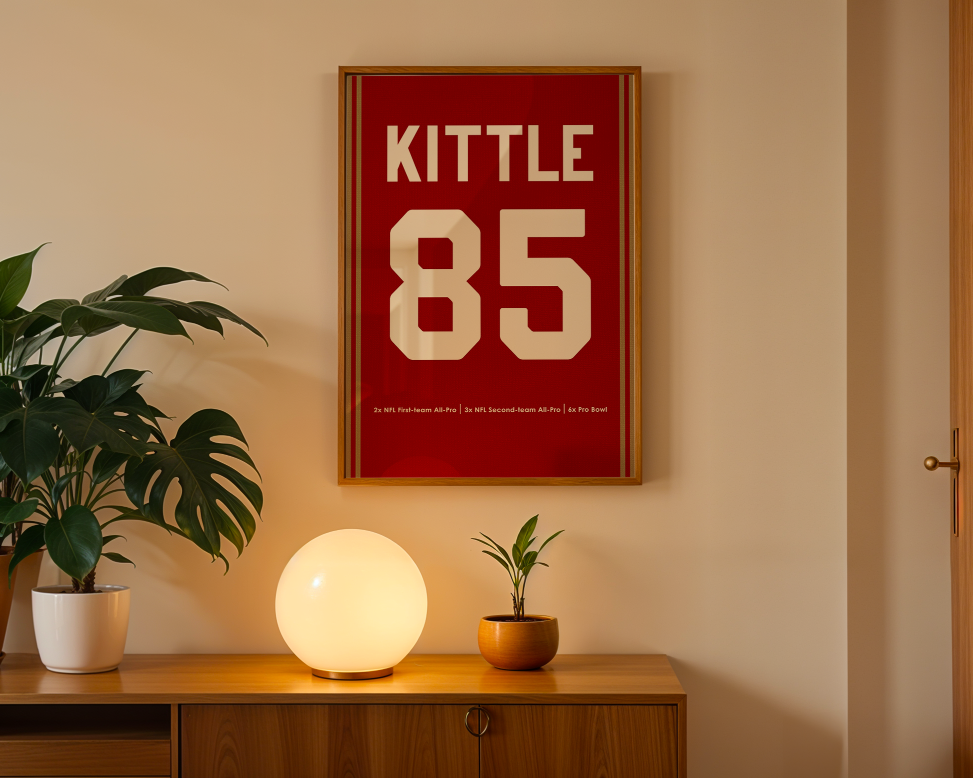 Framed poster with 'Kittle 85' on a wall above a wooden cabinet with decorative items.