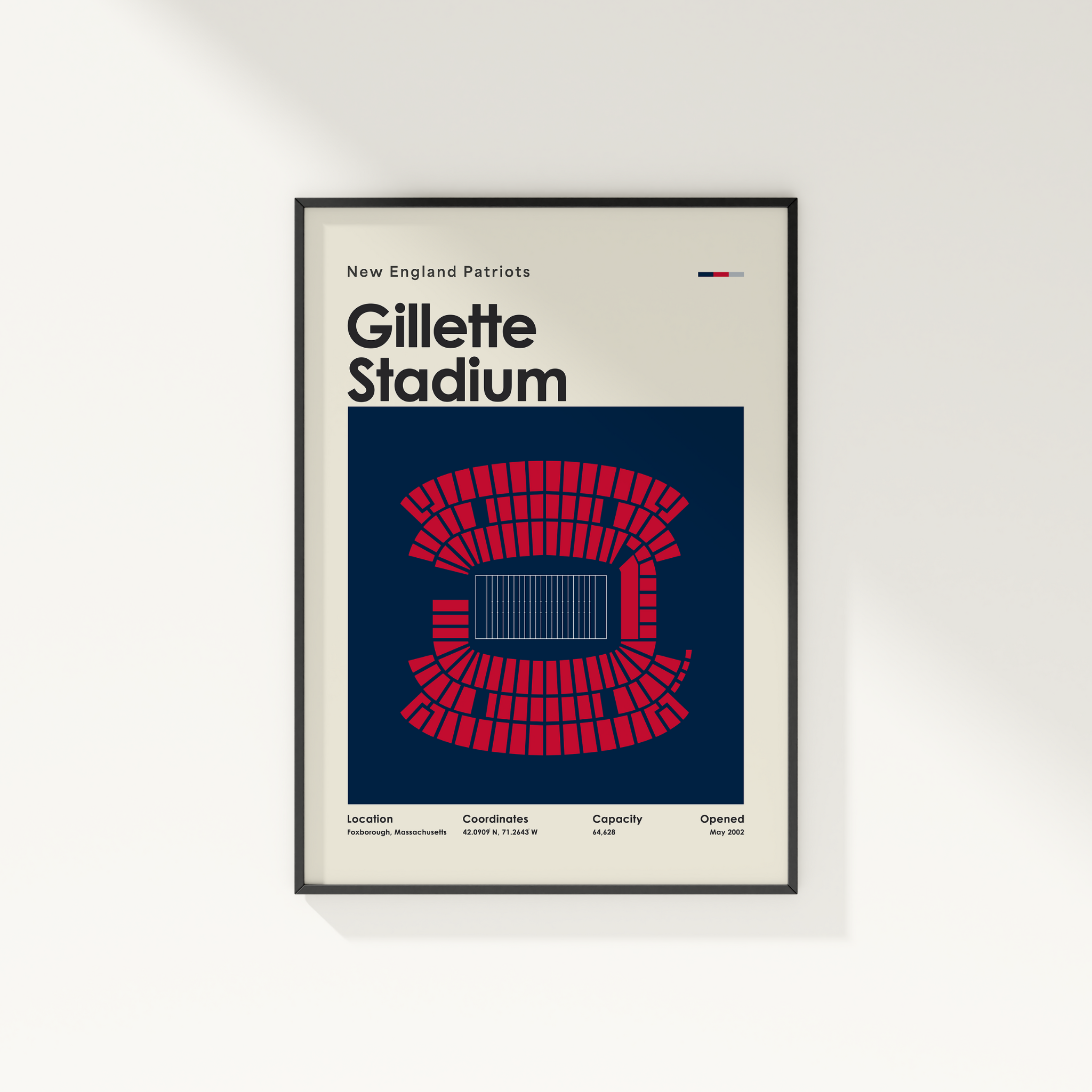 Framed poster of Gillette Stadium with seating layout and text on a white wall.