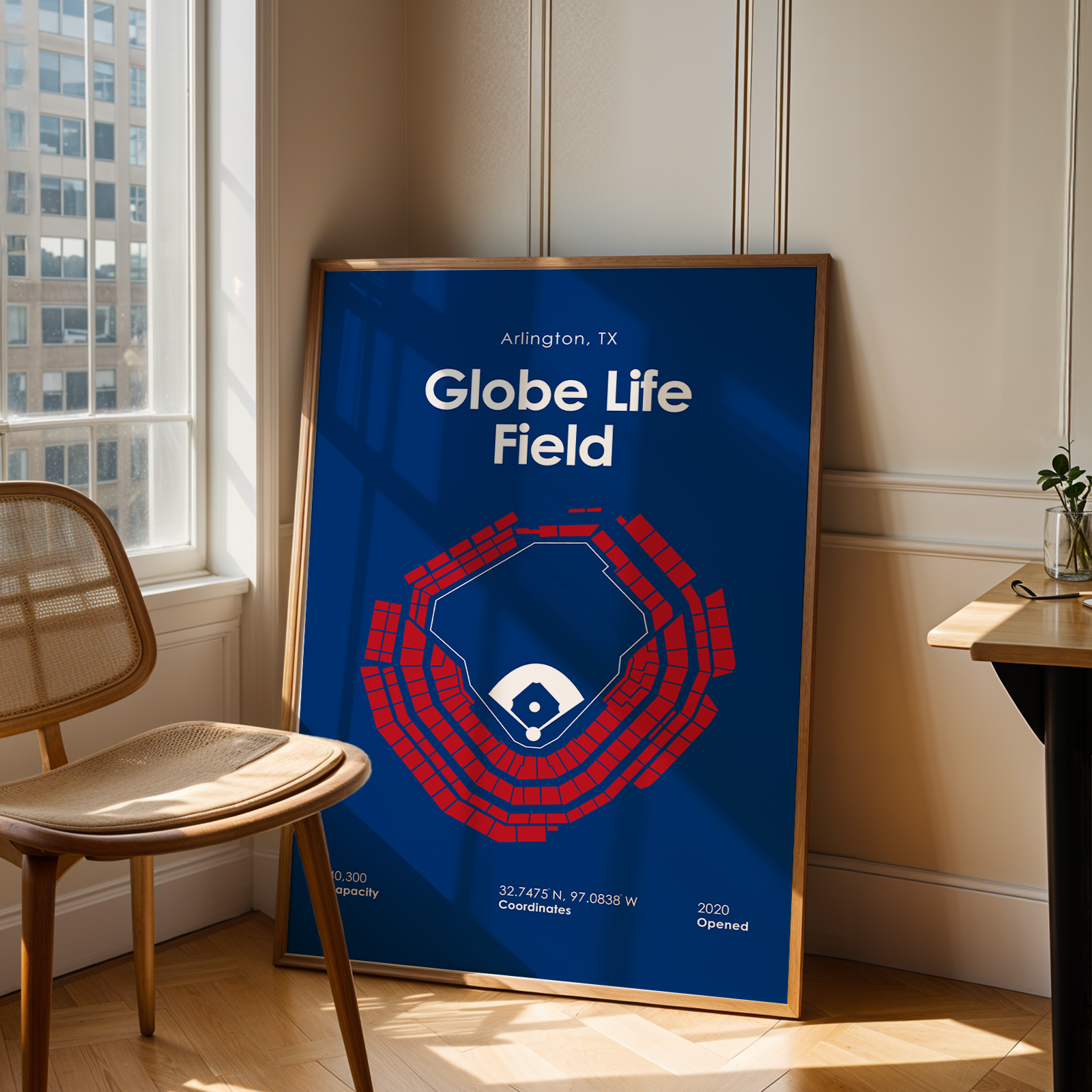 Framed poster of Globe Life Field in a room with a window and chair.