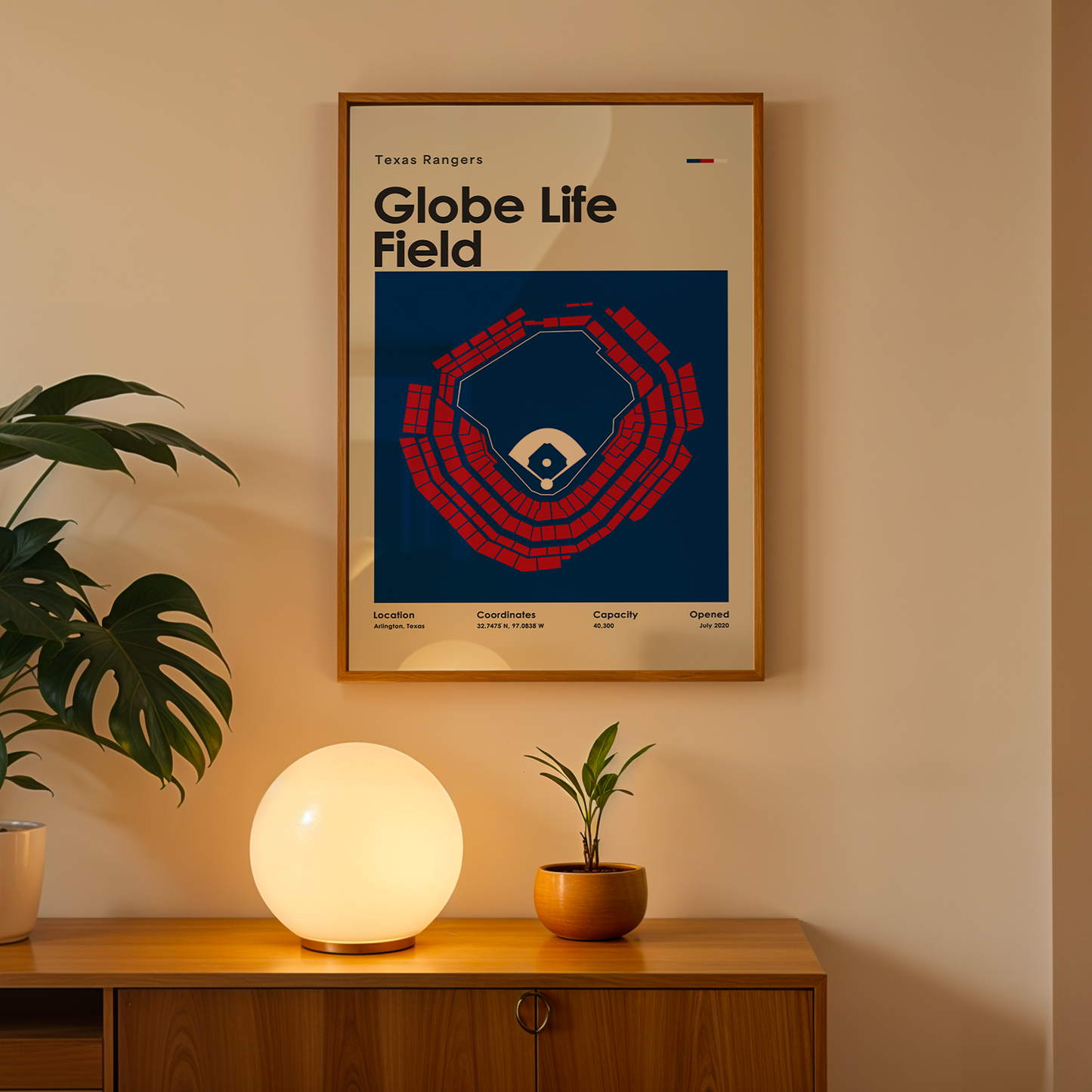 Framed poster of Globe Life Field on a wall above a wooden cabinet with decorative items.