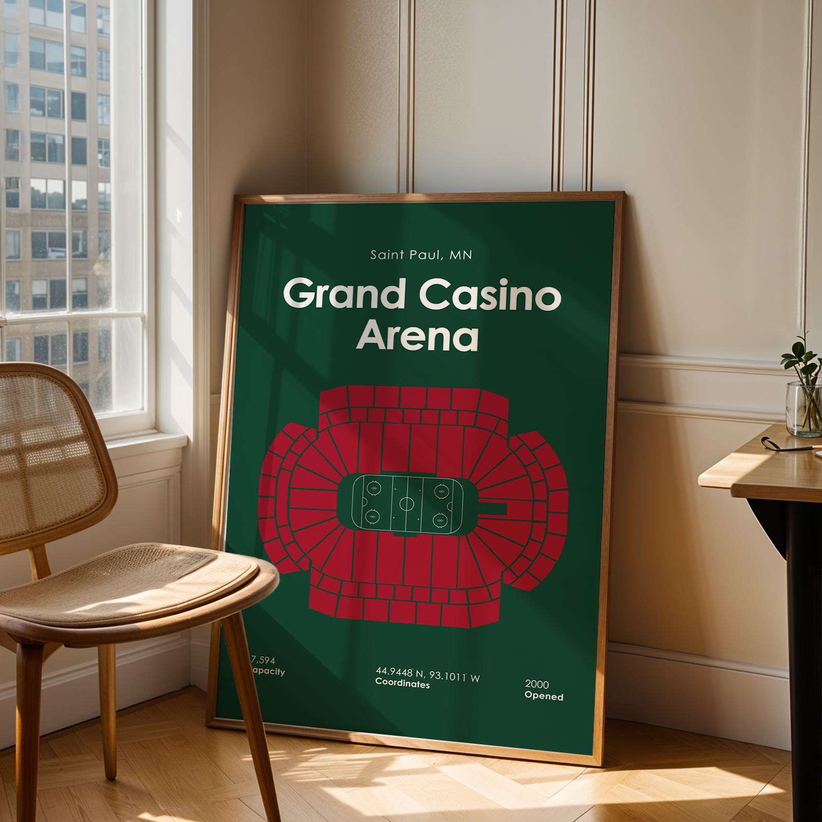 Framed poster of Grand Casino Arena in a room with a chair and window.