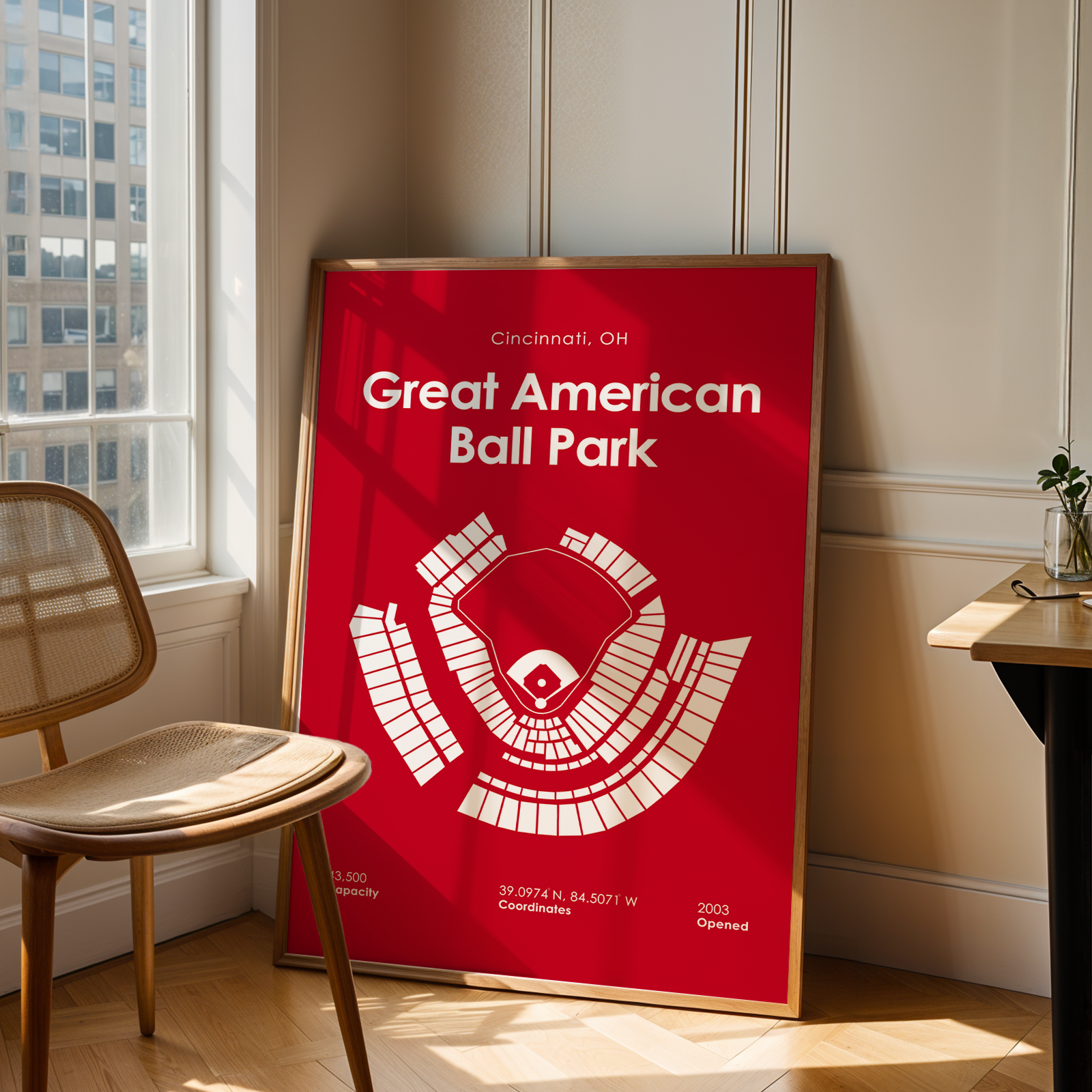 Framed poster of Great American Ball Park in a room with a window and chair.
