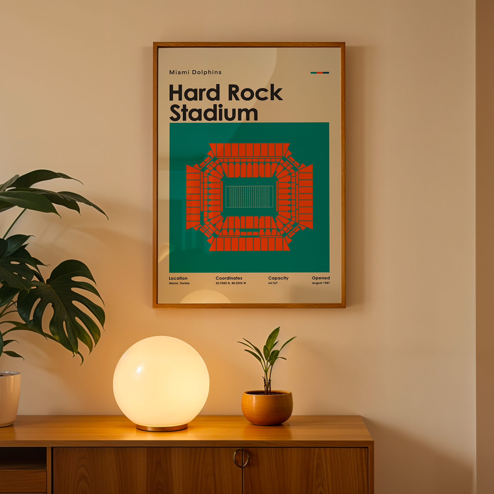 Framed poster of Hard Rock Stadium on a wall above a wooden cabinet with decorative items.