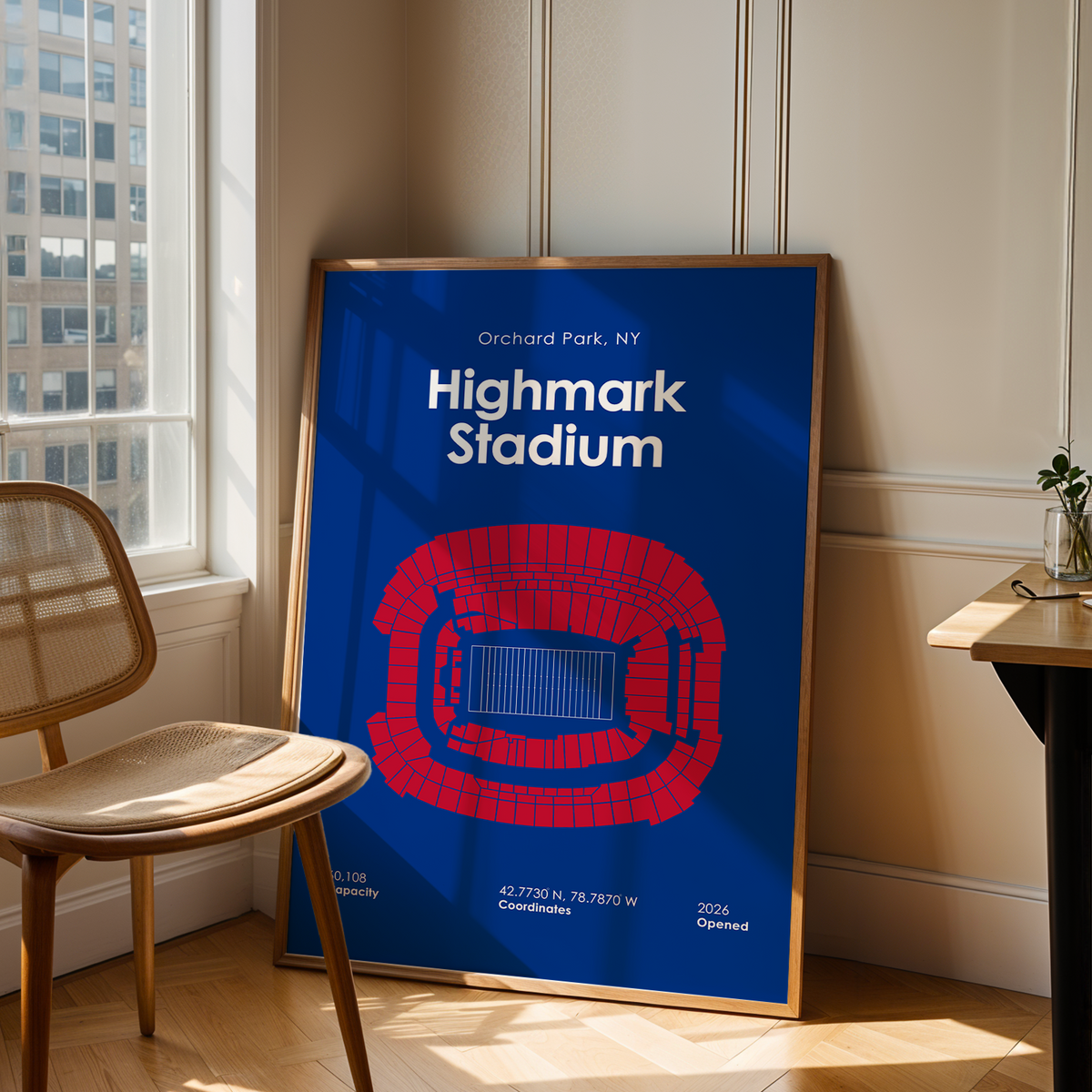 A framed poster of a football stadium map for Highmark Stadium in Orchard Park, NY, leaning against a wall in a modern room with a wooden chair and desk.