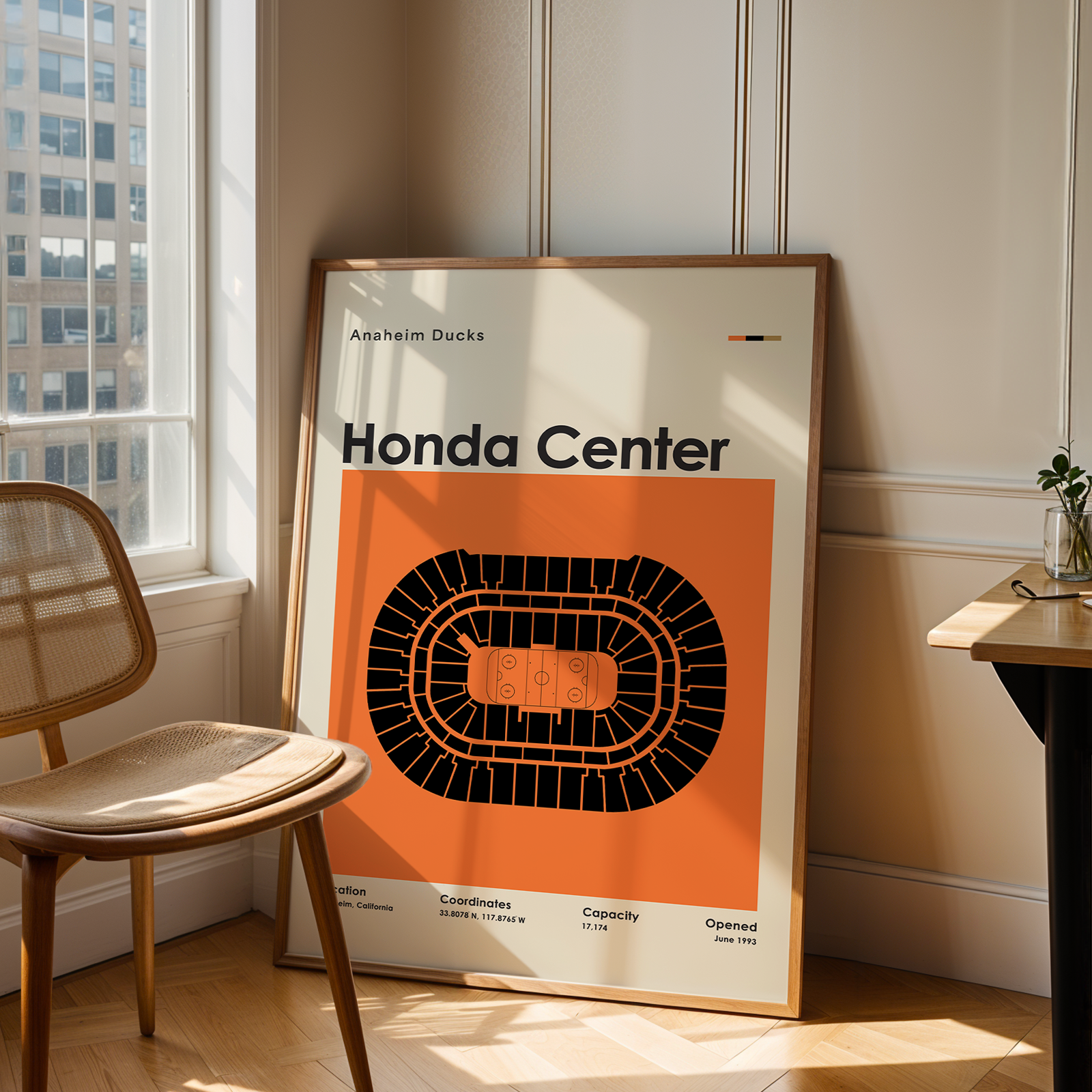 Framed poster of Honda Center in a room with a chair and table.