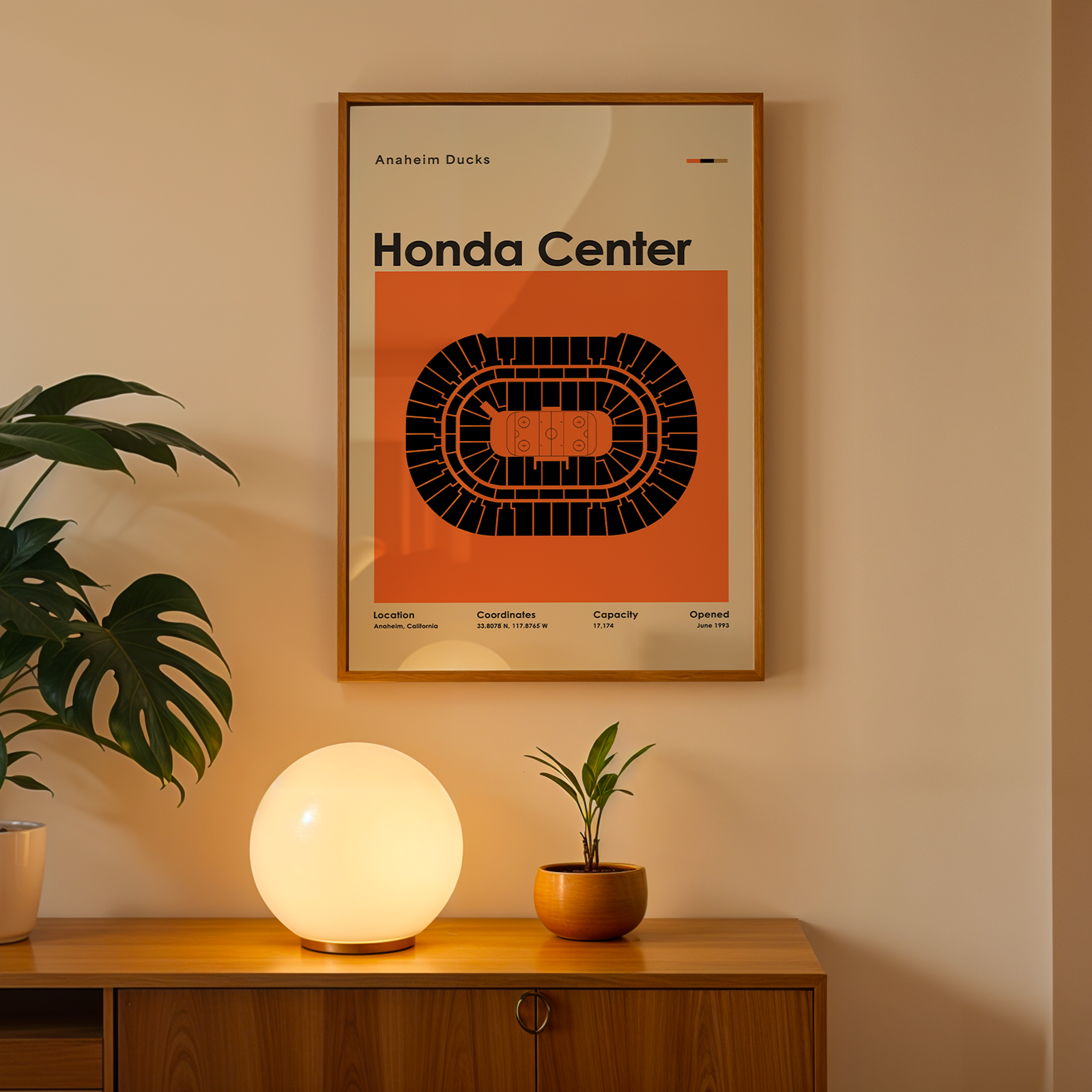 Framed poster of Honda Center on a wall above a wooden cabinet with decorative items.