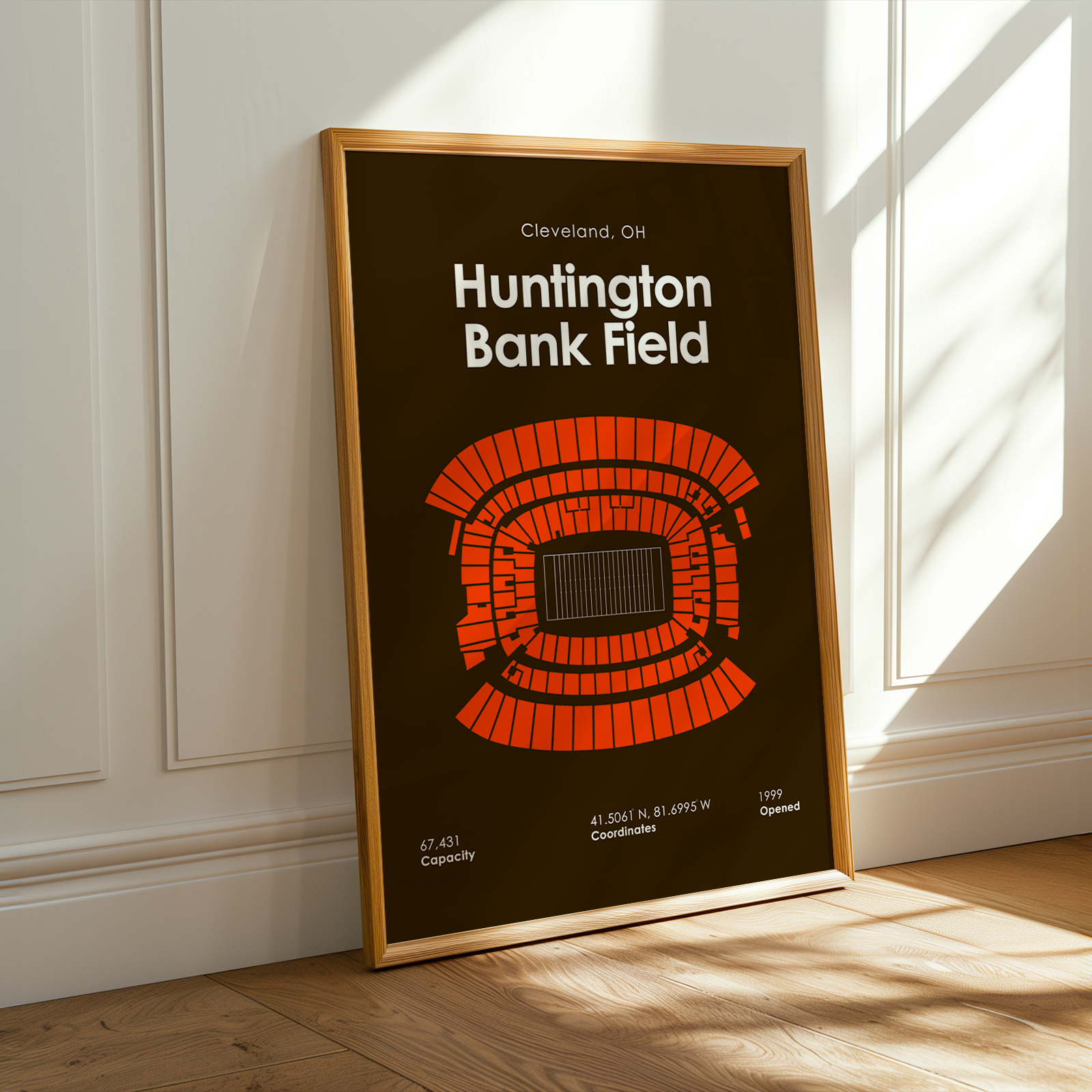 Framed poster of Huntington Bank Field in Cleveland, Ohio on a wooden floor with sunlight streaming in.