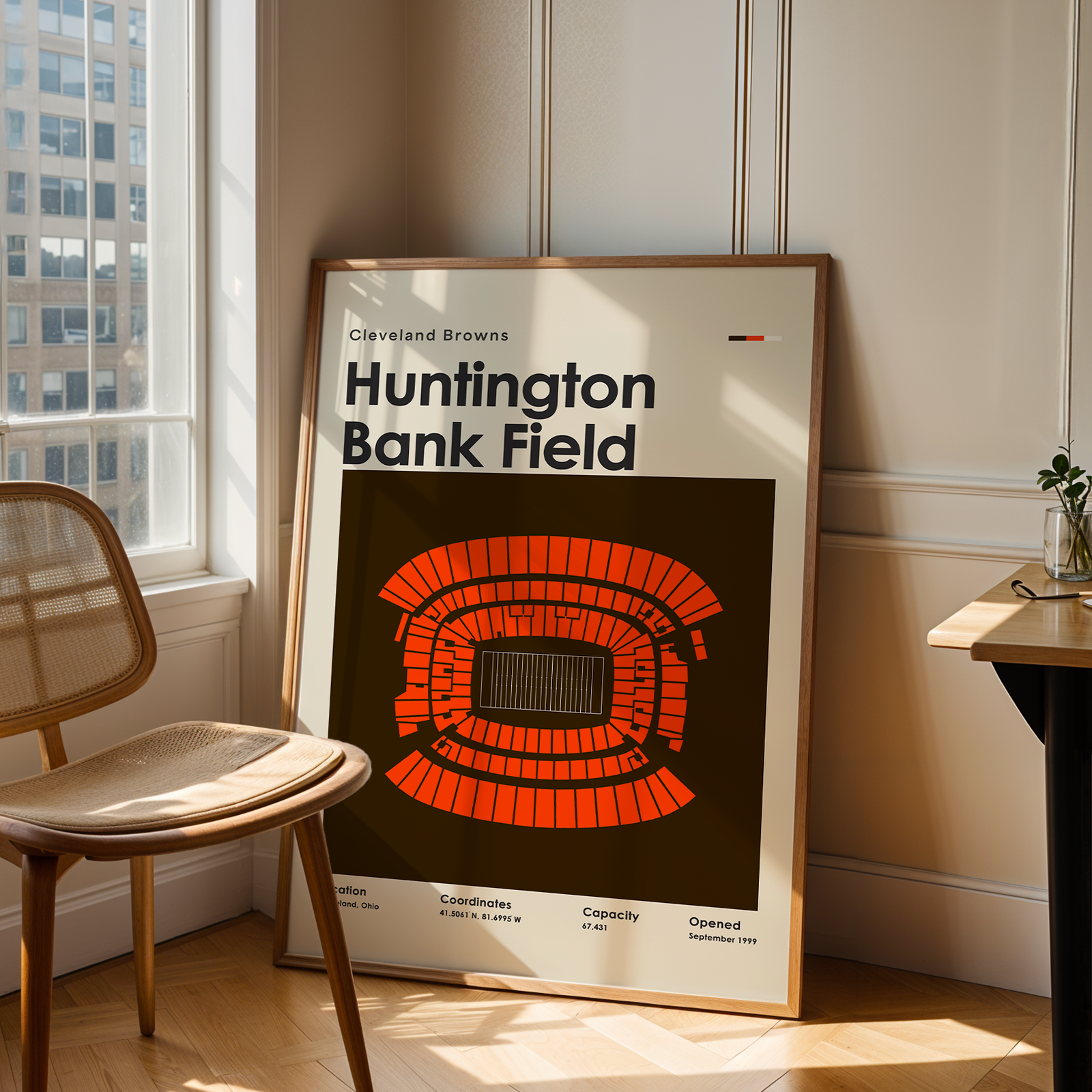 Framed poster of Huntington Bank Field in a room with a window and chair.