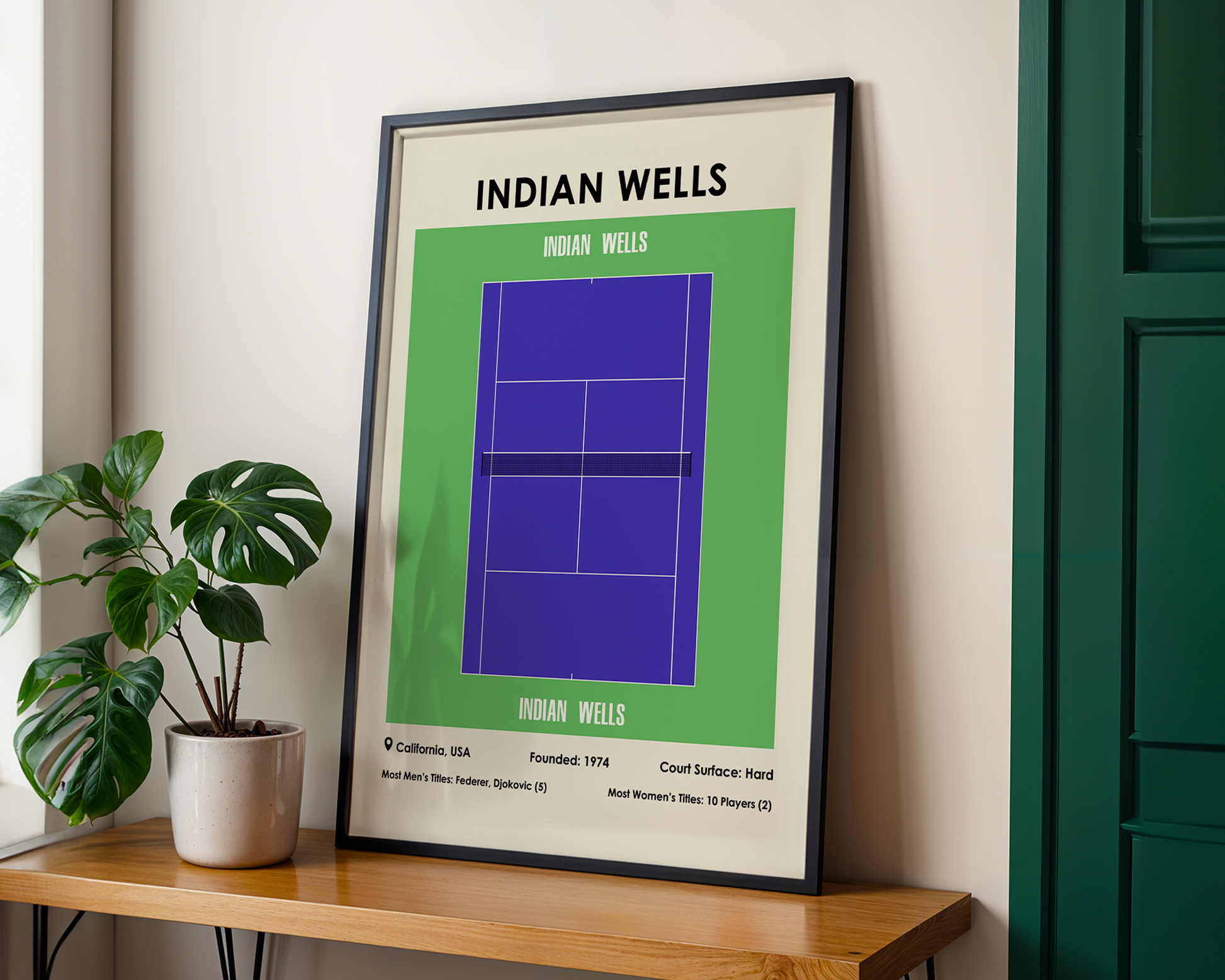 Framed poster of Indian Wells tennis court design on a wall with a plant below.
