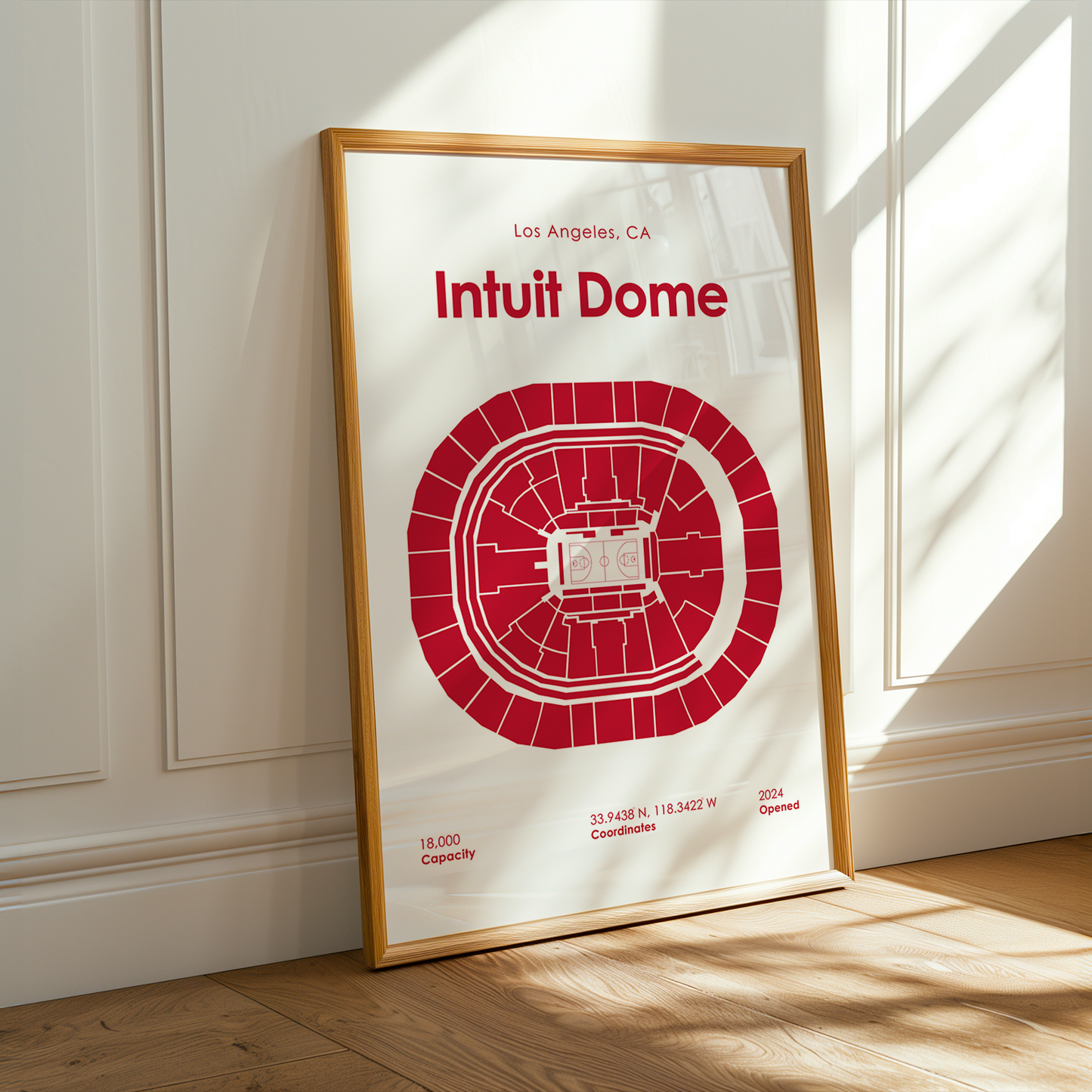 Framed poster of Intuit Dome with red design on a white background, leaning against a wall.