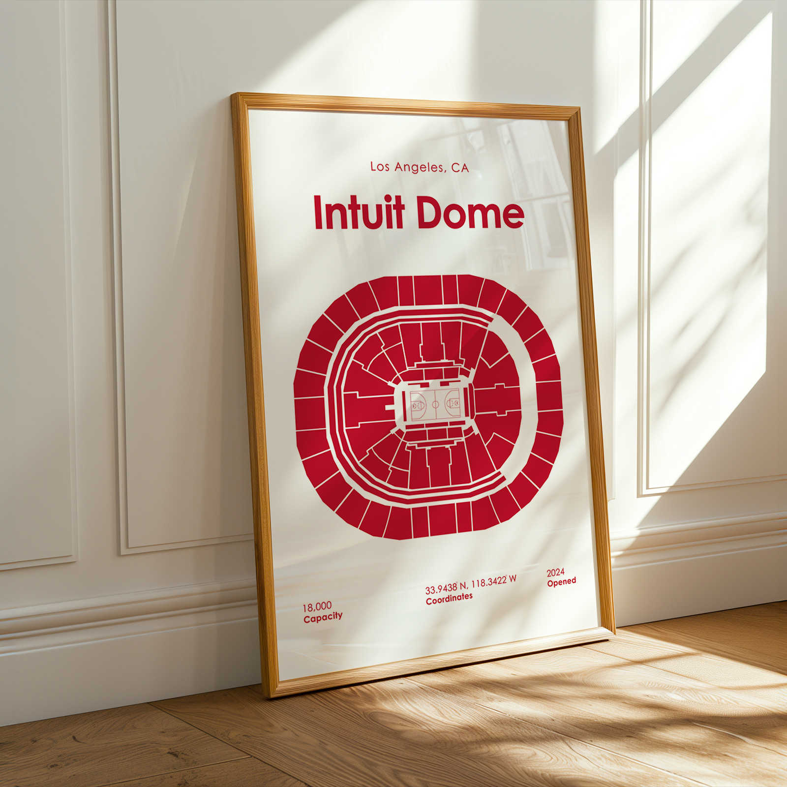 Framed poster of Intuit Dome with red design on a white background, leaning against a wall.