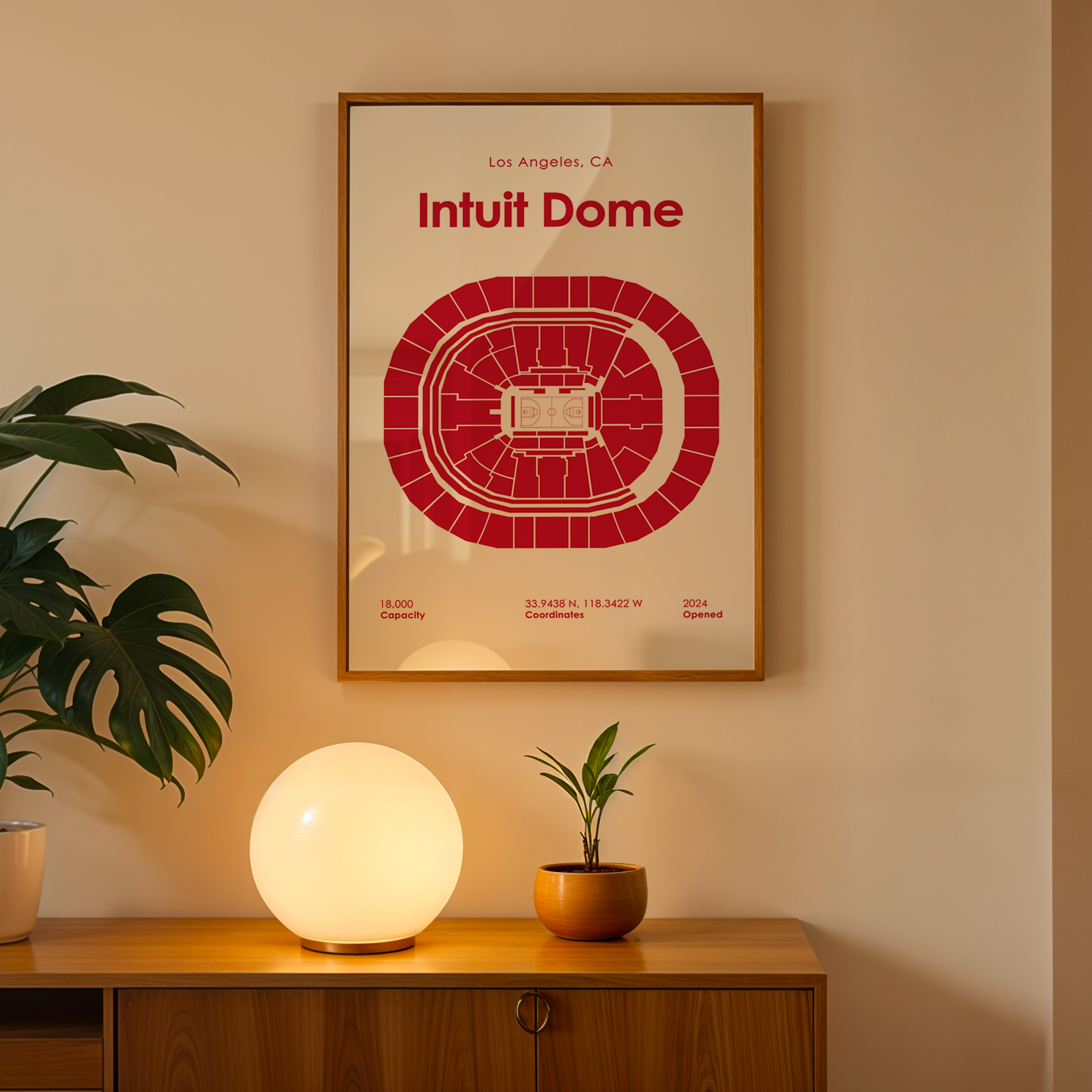 Framed 'Intuit Dome' poster on a wall above a wooden cabinet with decorative items.