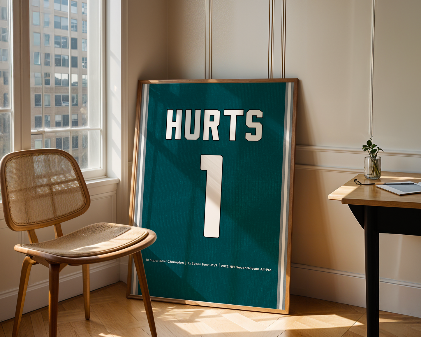 Framed poster with 'HURTS' and number '1' in a room with a chair and table.