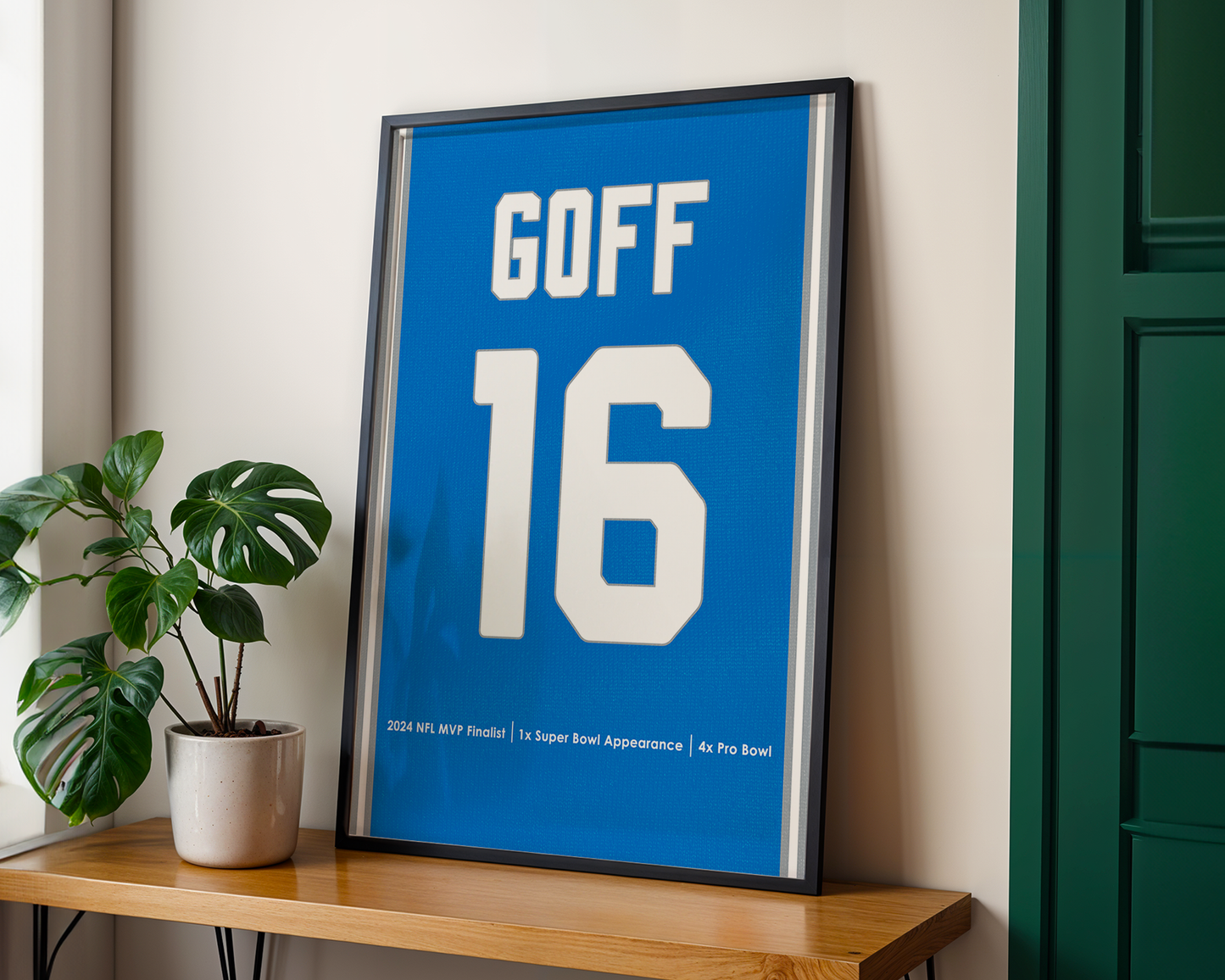 Framed sports jersey with 'GOFF 16' on a wooden shelf with a plant