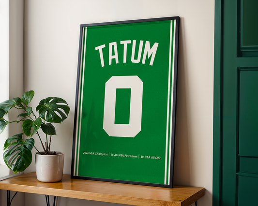 Framed sports jersey with 'Tatum' and number '0' on a wooden shelf.
