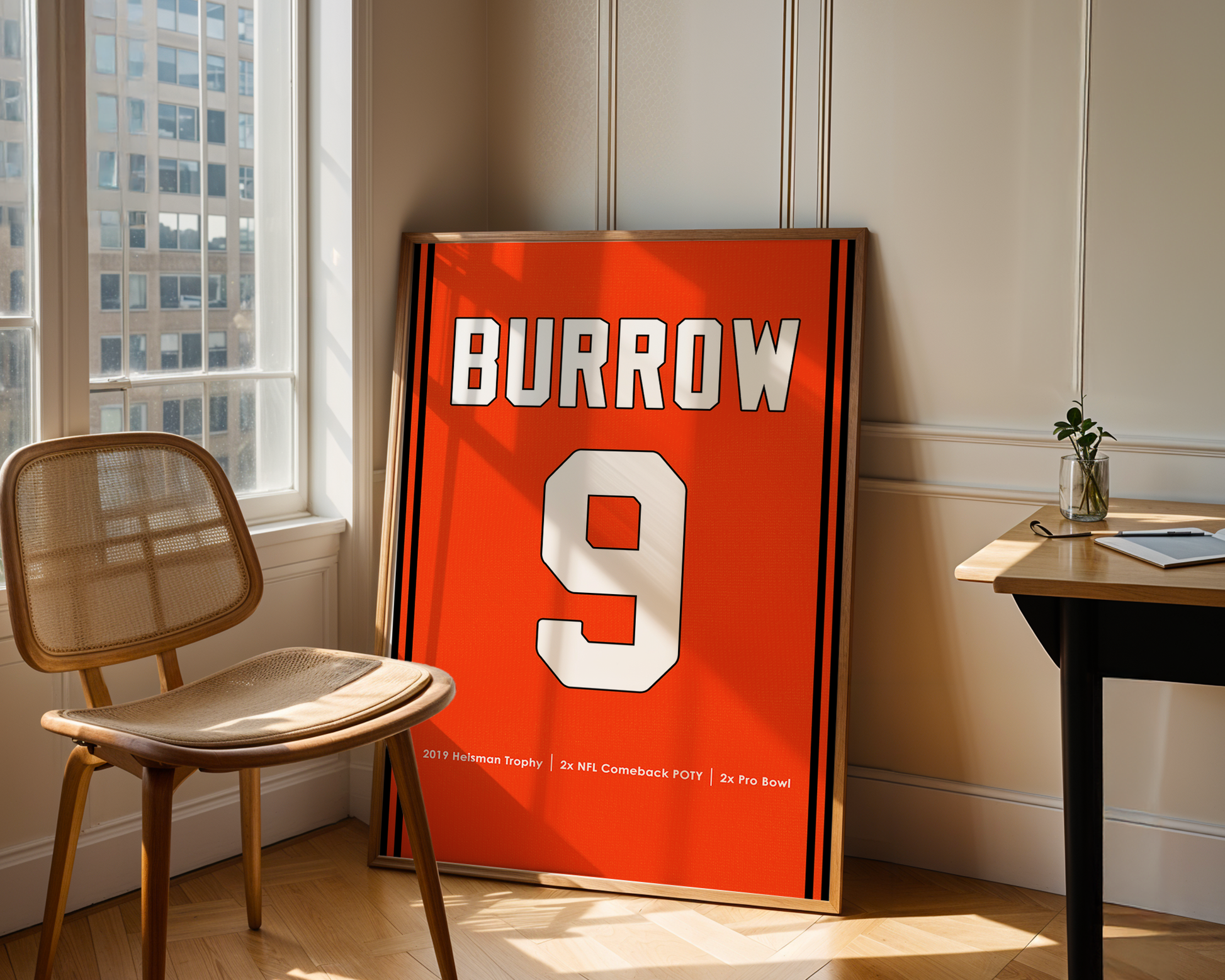 Orange sports jersey with 'BURROW 9' printed on it, leaning against a wall in a room with a chair and table.