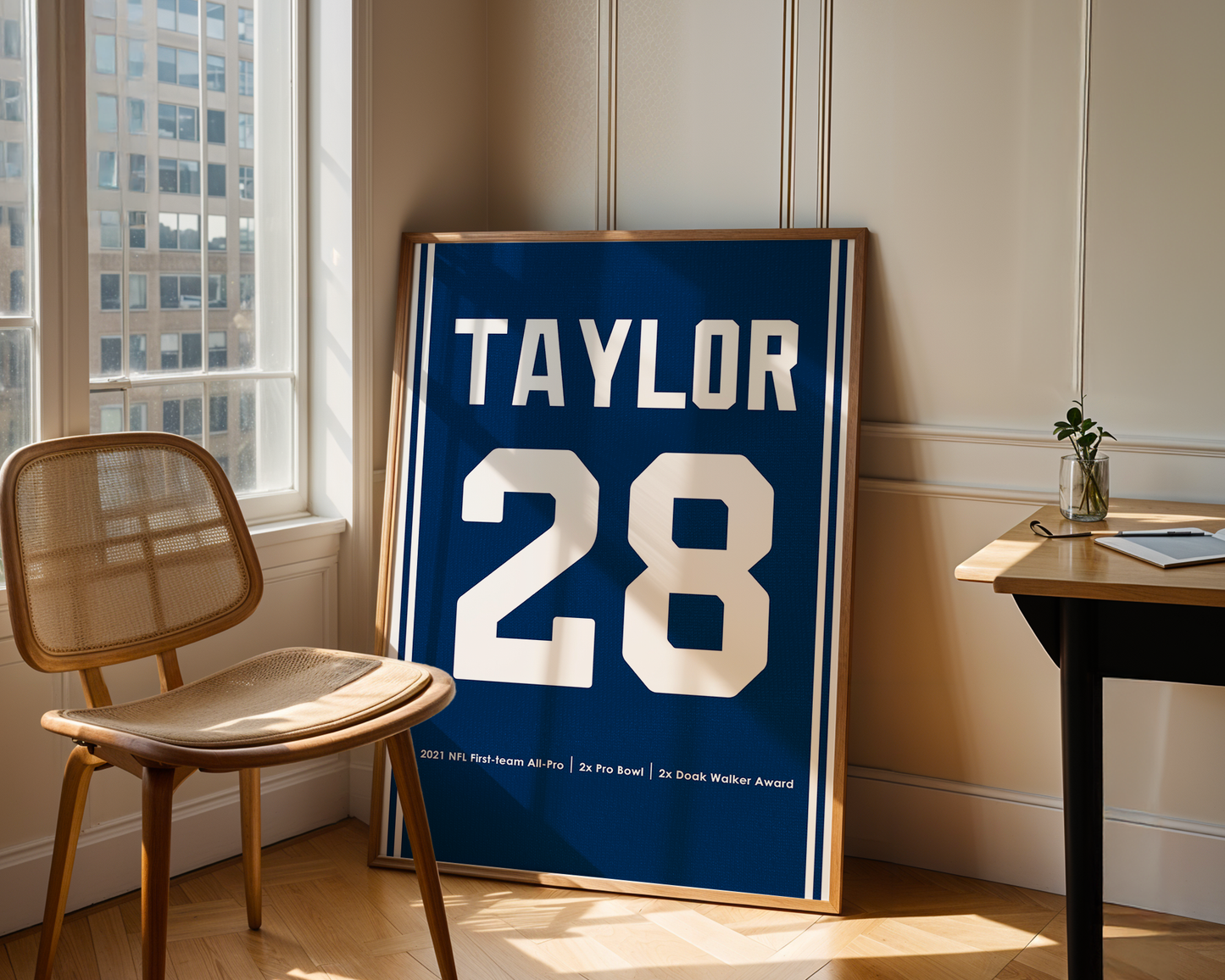 Framed sports jersey with 'Taylor' and number '28' in a room with a window and chair.