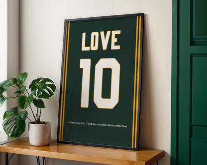 Framed poster with 'LOVE 10' on a wooden shelf next to a plant