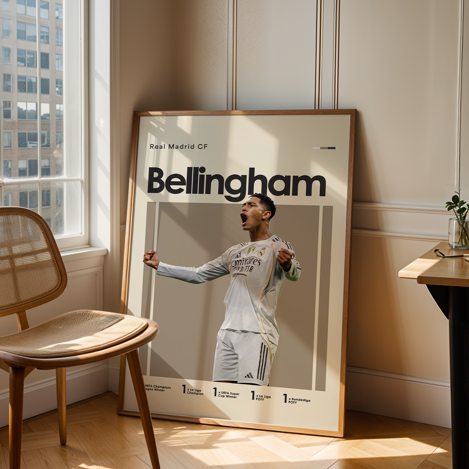 Poster of a soccer player with 'Bellingham' on it, leaning against a wall in a room with a chair and table.