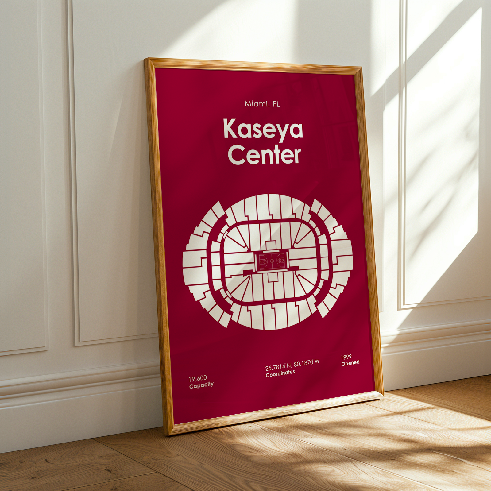 Framed poster of Kaseya Center with a red background and white text, leaning against a white wall.