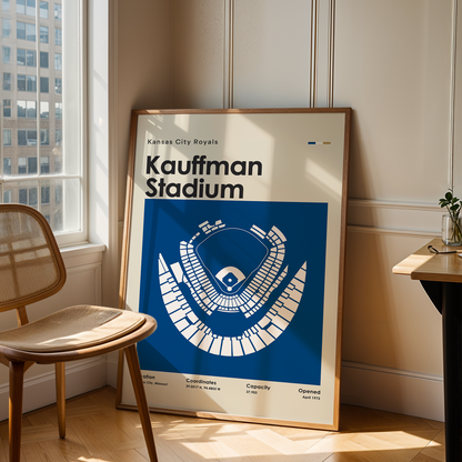 Framed poster of Kauffman Stadium in a room with a chair and table.