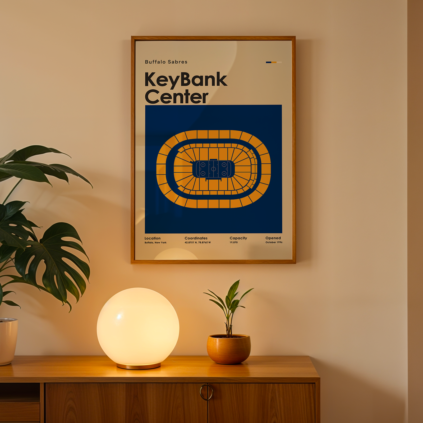 Framed poster of KeyBank Center on a wall above a wooden cabinet with decorative items.