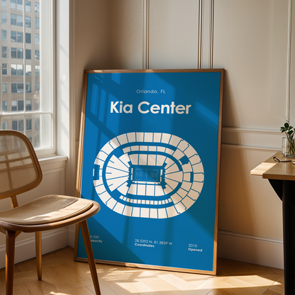 Framed poster of the Kia Center in Orlando, FL, leaning against a wall next to a chair and table.
