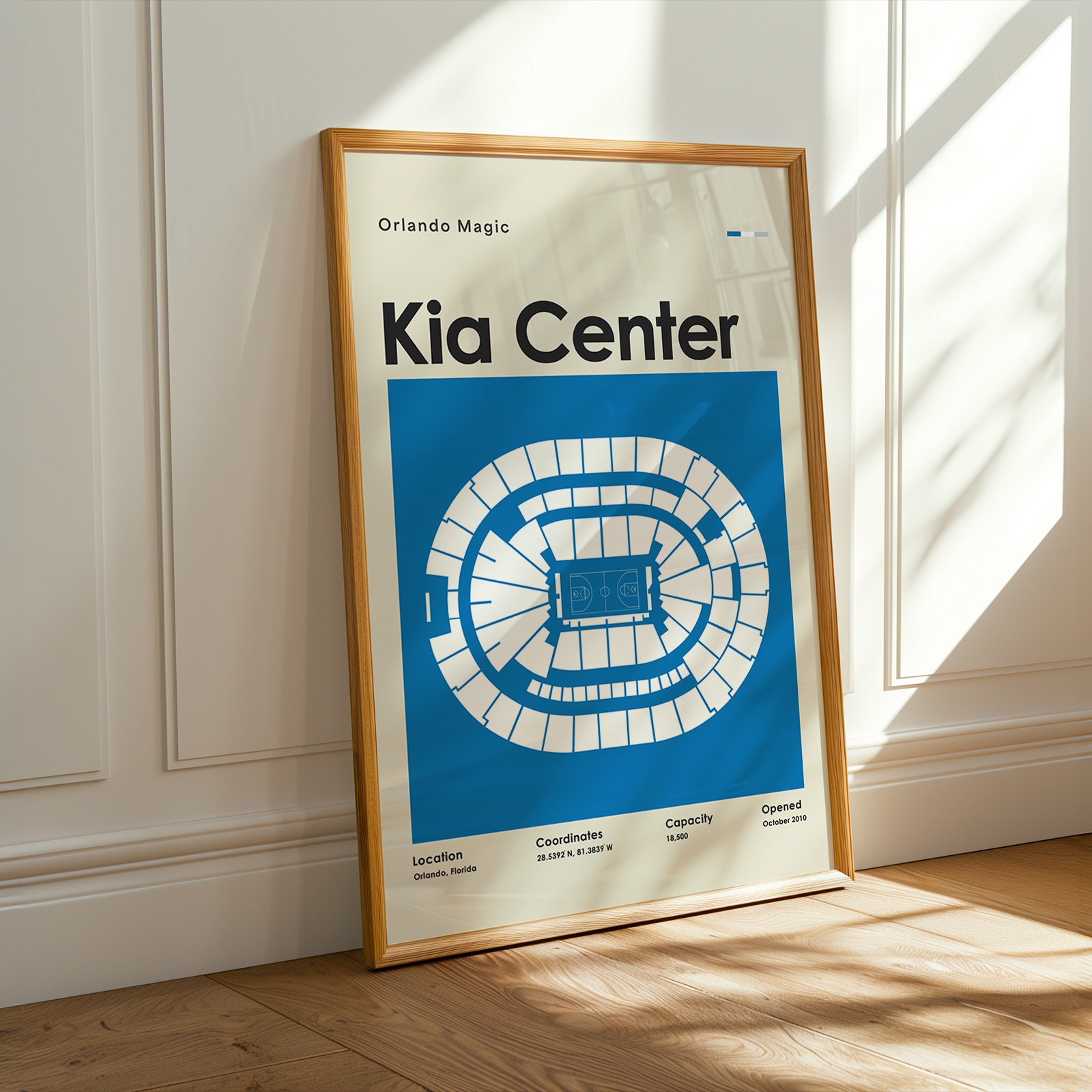 Framed poster of the Kia Center layout on a wooden floor with sunlight streaming through a window.