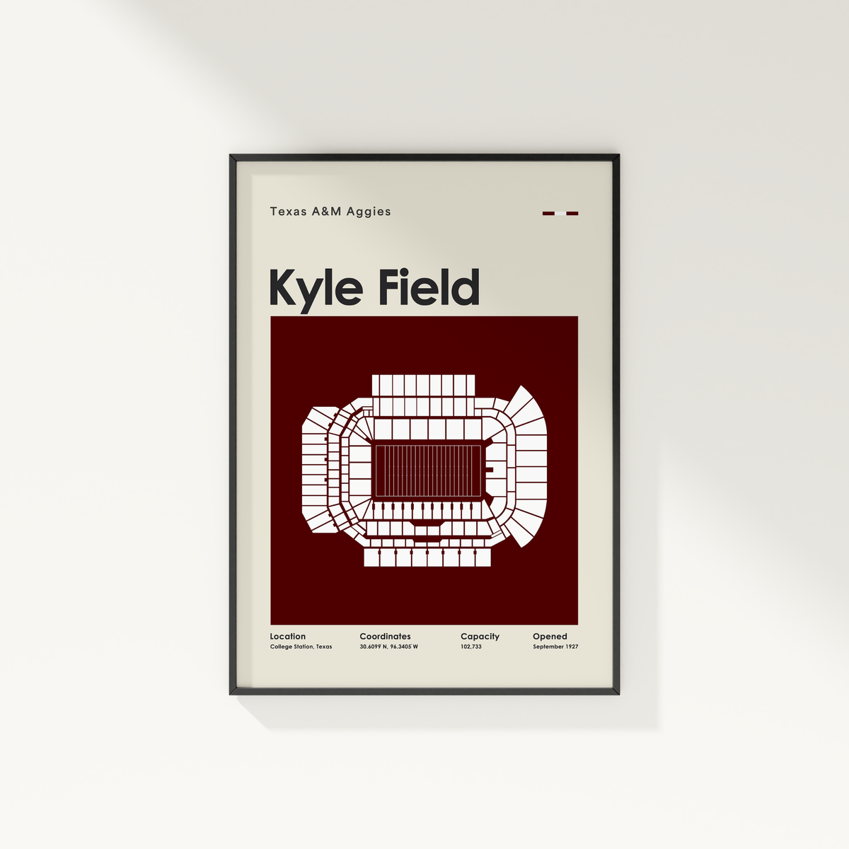 A framed minimalist poster of Texas A&M Kyle Field stadium, featuring a white stadium floor plan on a deep maroon background, mounted on a light beige wall.