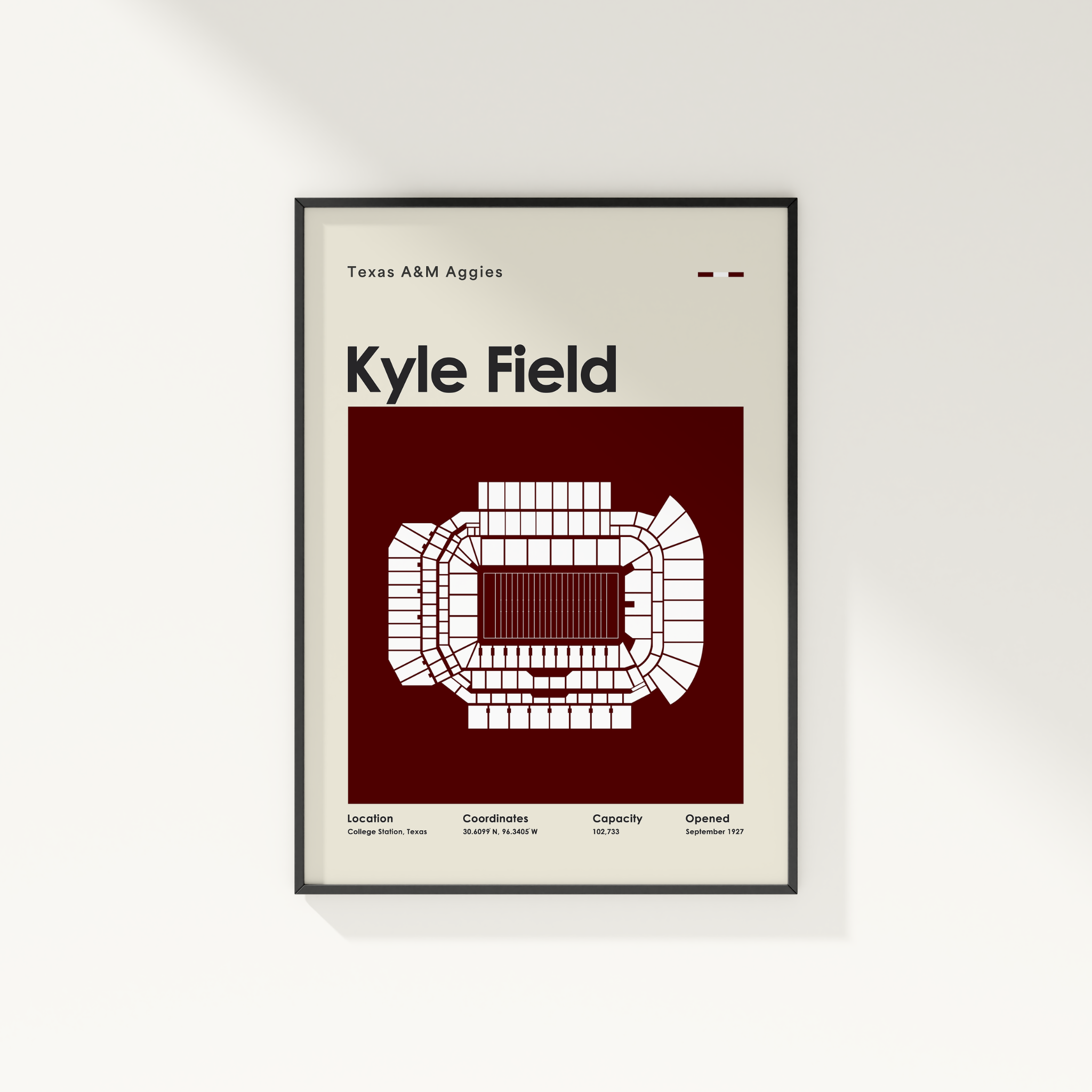 A framed minimalist poster of Texas A&M Kyle Field stadium, featuring a white stadium floor plan on a deep maroon background, mounted on a light beige wall.