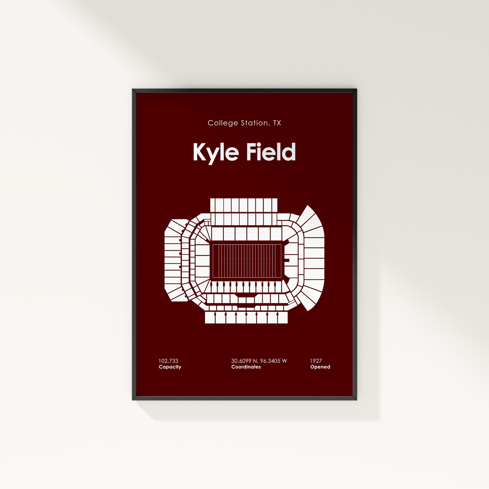 A framed vertical poster featuring a white stadium floor plan and text for Kyle Field, College Station, TX, on a dark red background, shown hanging on a light wall.