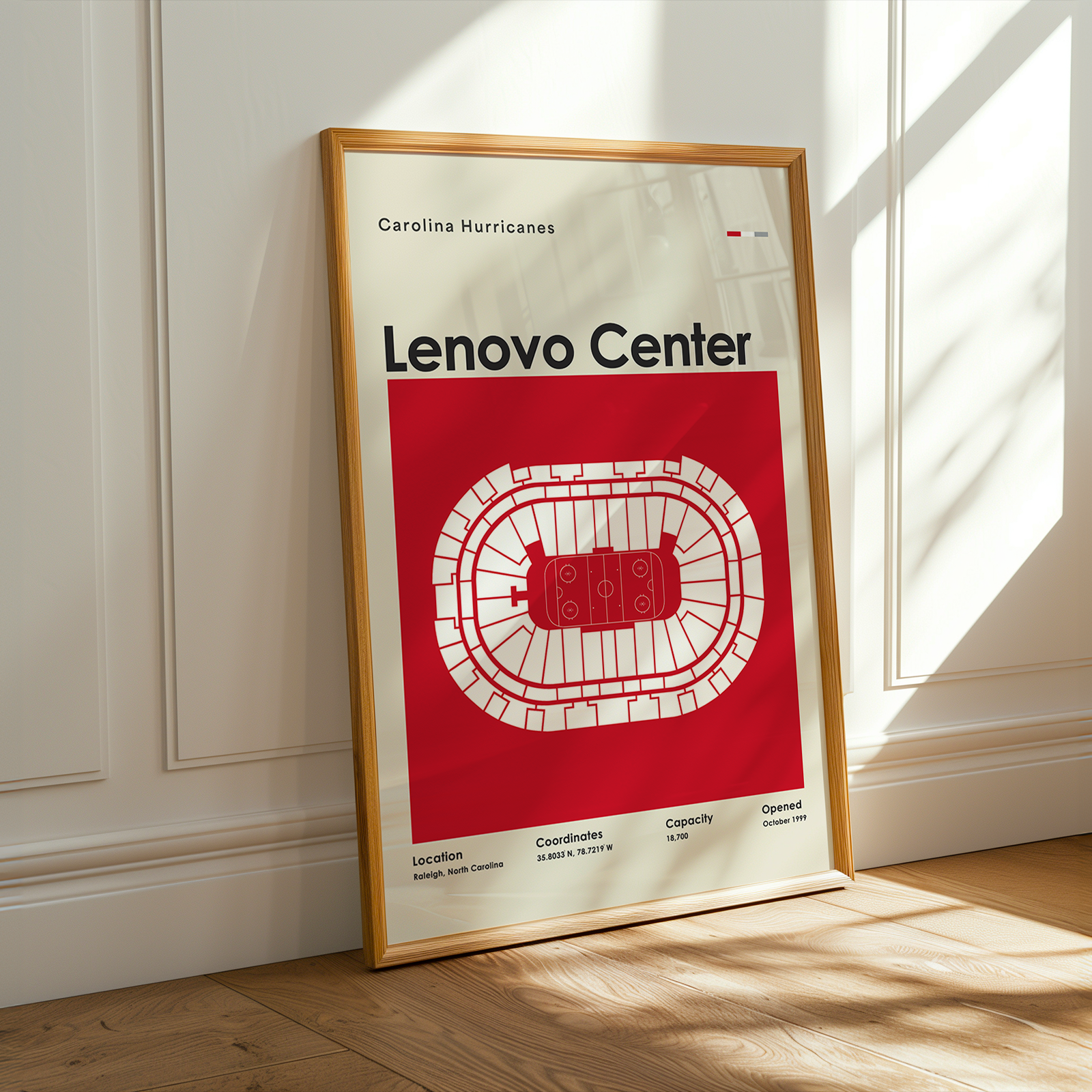 Framed poster of Carolina Hurricanes Lenovo Center on a wooden floor with sunlight streaming through a window.