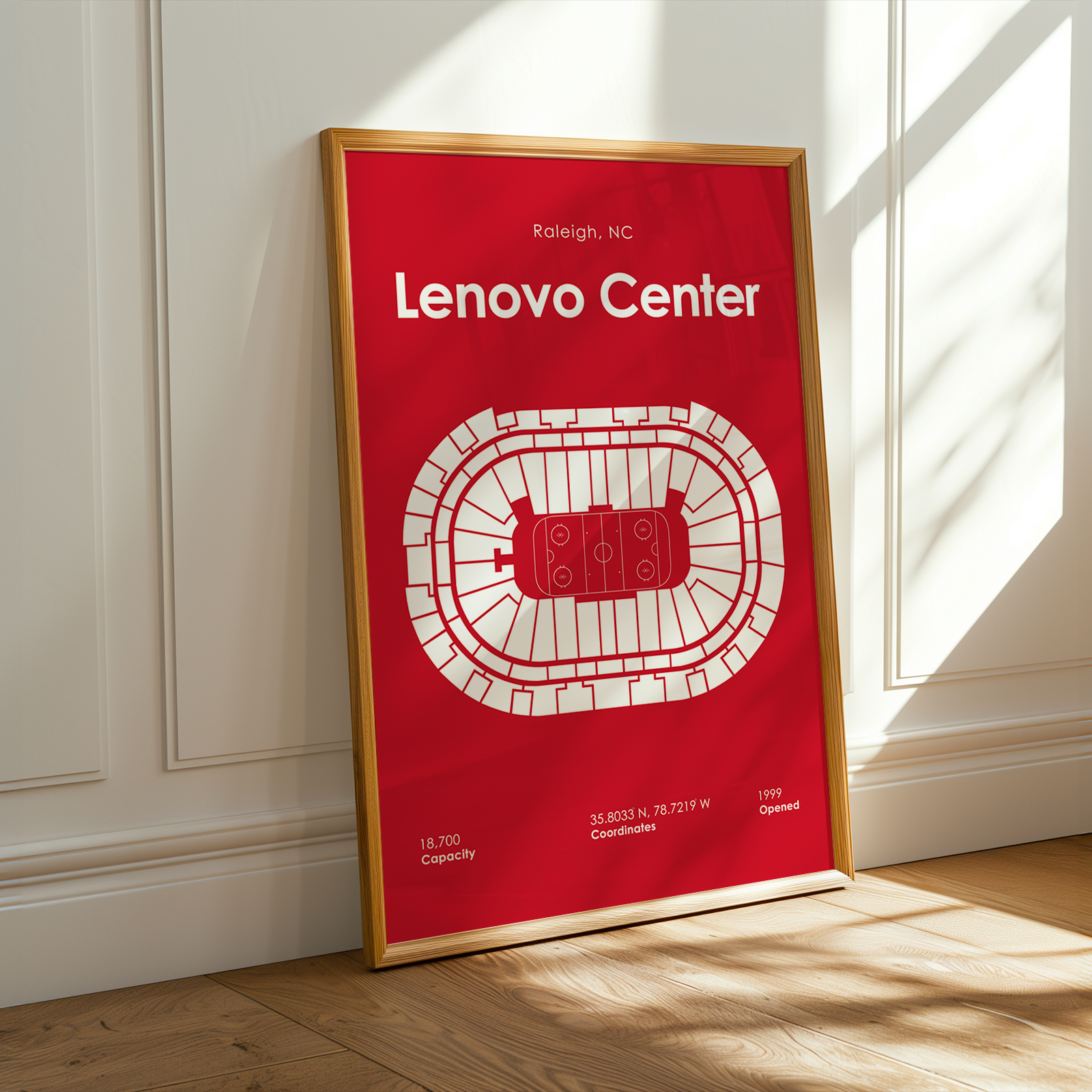 Framed poster of Lenovo Center with red background and white text, leaning against a white wall.