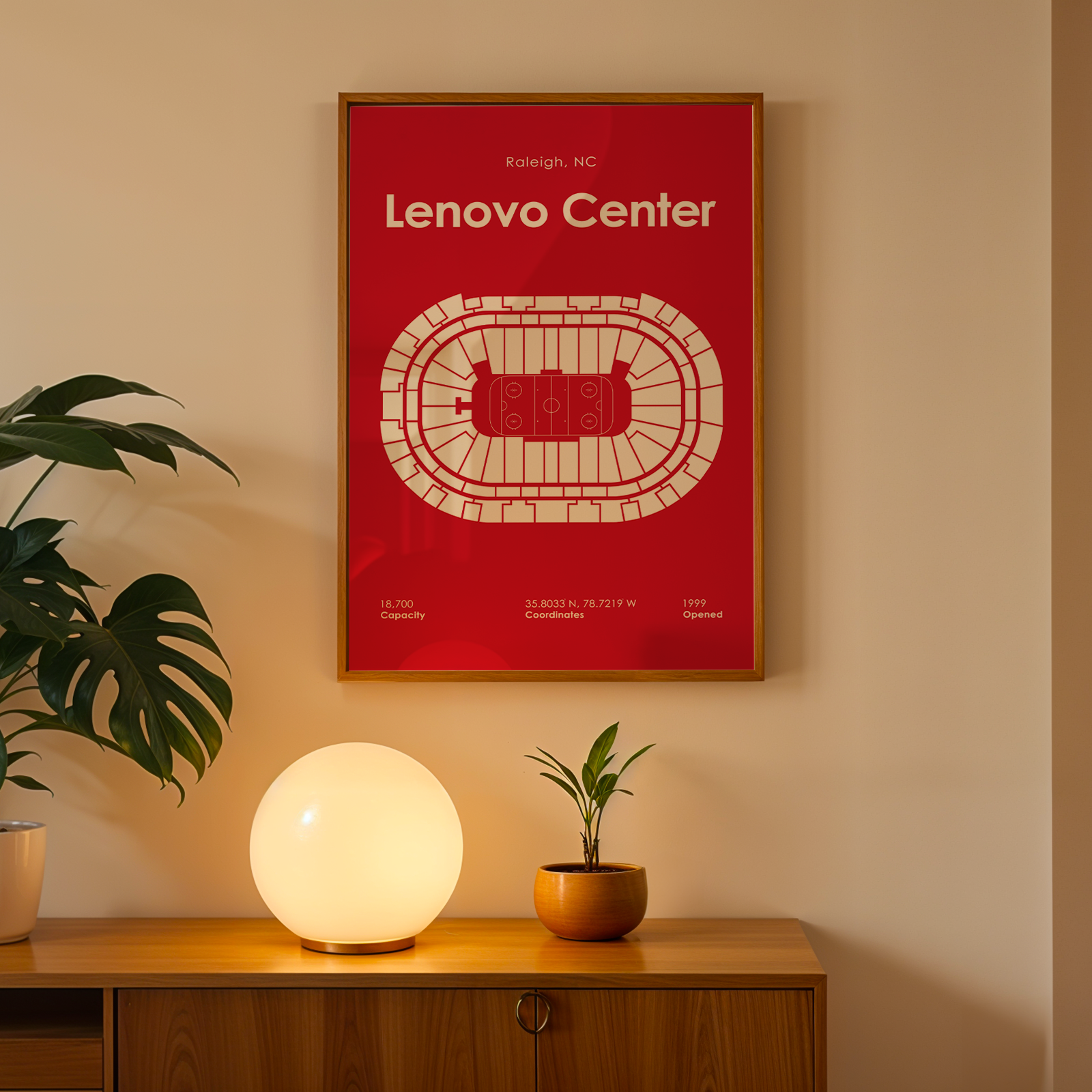 Framed Lenovo Center poster on a wall with a lamp and plant below.