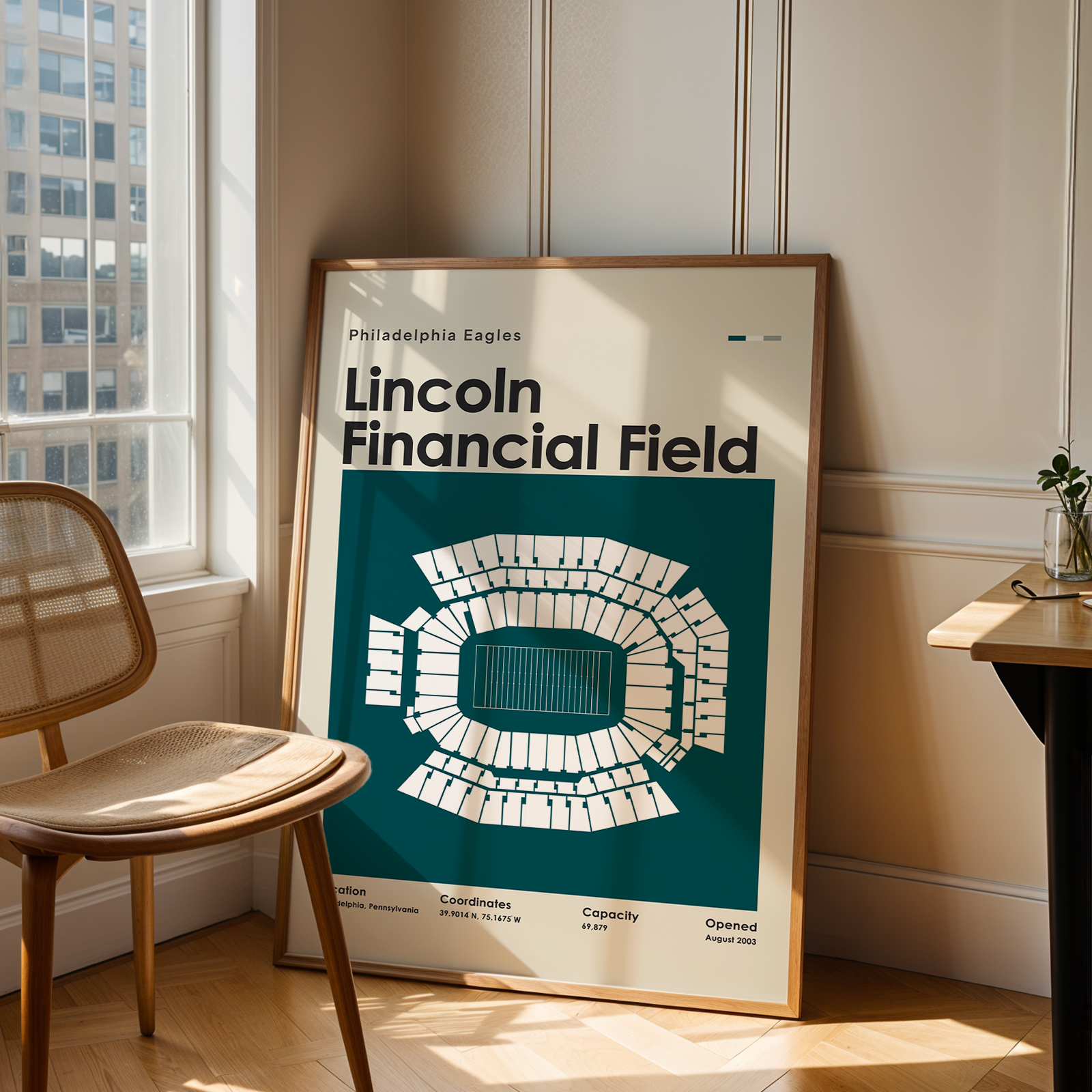 Framed poster of Lincoln Financial Field in a room with a window and chair.