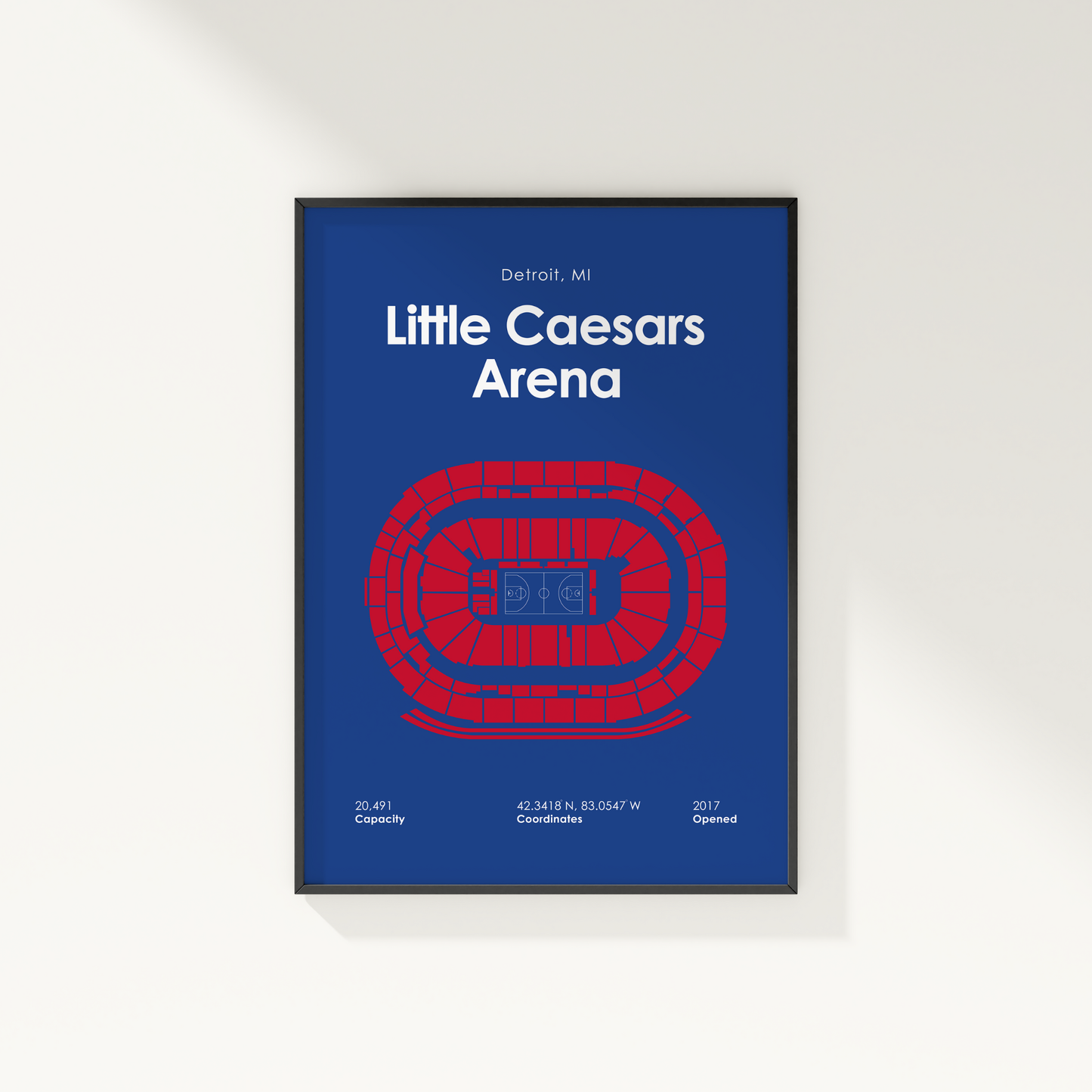 Framed poster of Little Caesars Arena with blue background and red arena illustration.