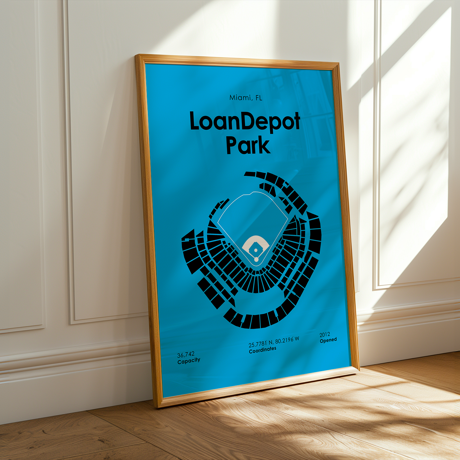 Framed poster of LoanDepot Park with blue background and black text, leaning against a white wall.