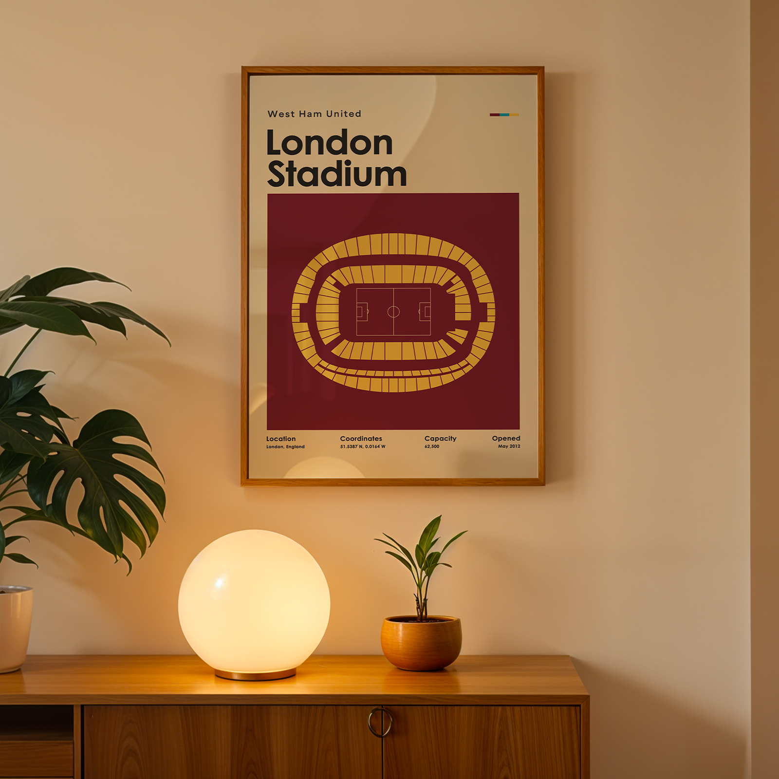 Framed poster of London Stadium on a wall above a wooden cabinet with decorative items.