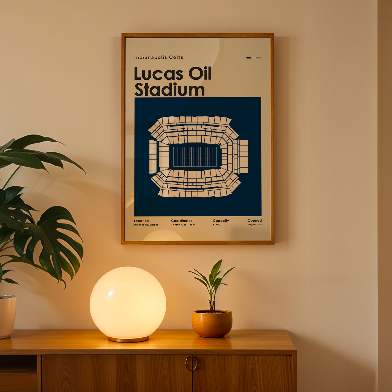 Framed poster of Lucas Oil Stadium on a wall above a wooden cabinet with decorative items.