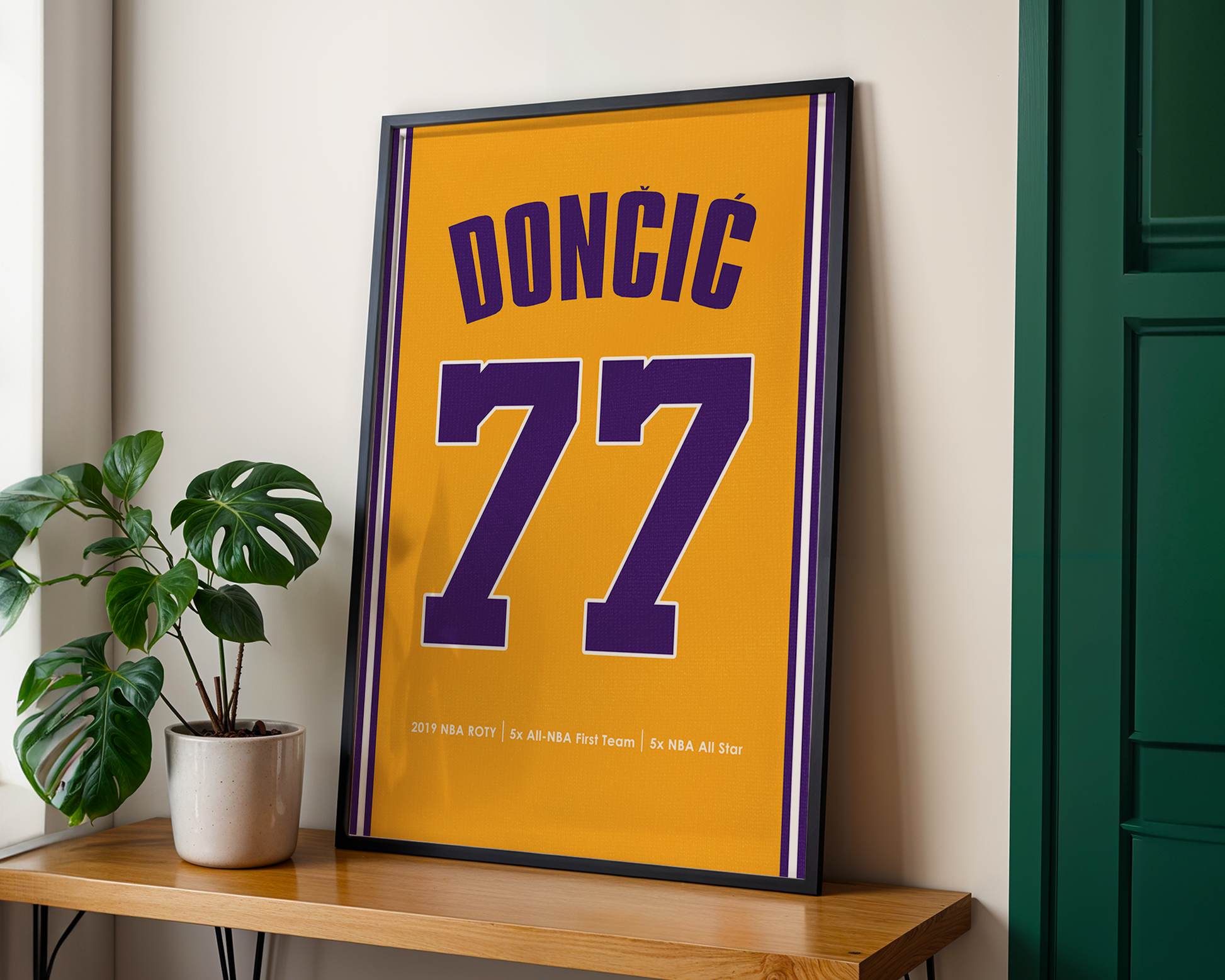 Framed sports jersey with 'DONCIC 77' on a wooden shelf with a plant.
