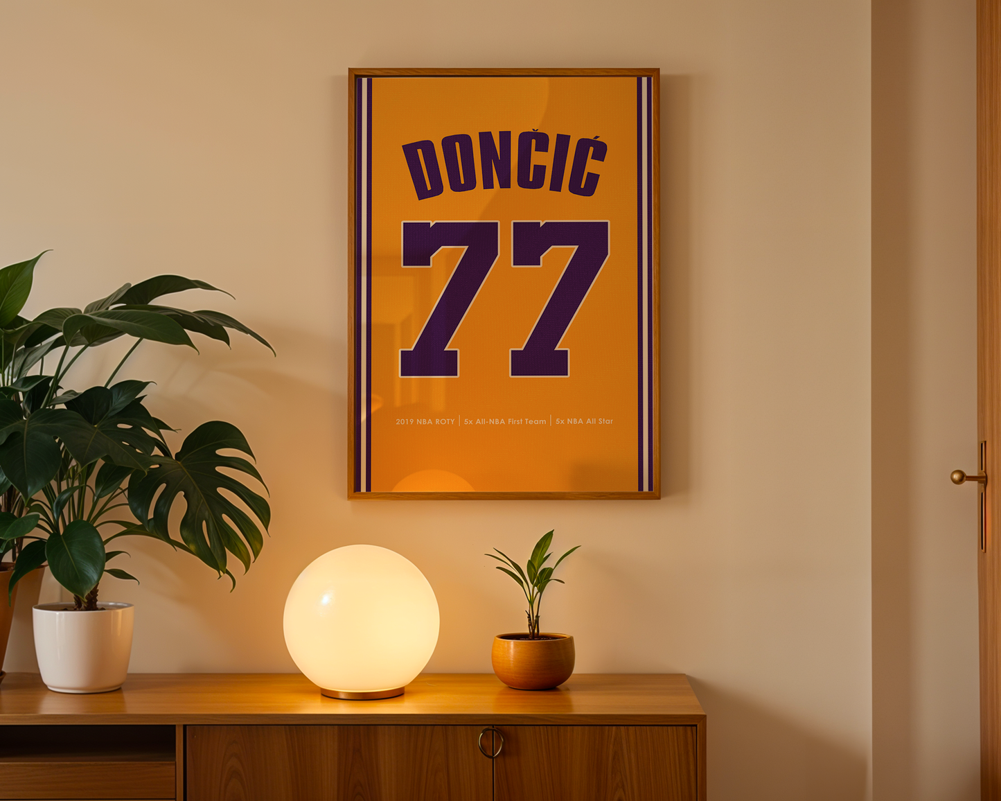 Framed poster with 'DONCIC 77' on an orange background, placed above a wooden cabinet with decorative items.