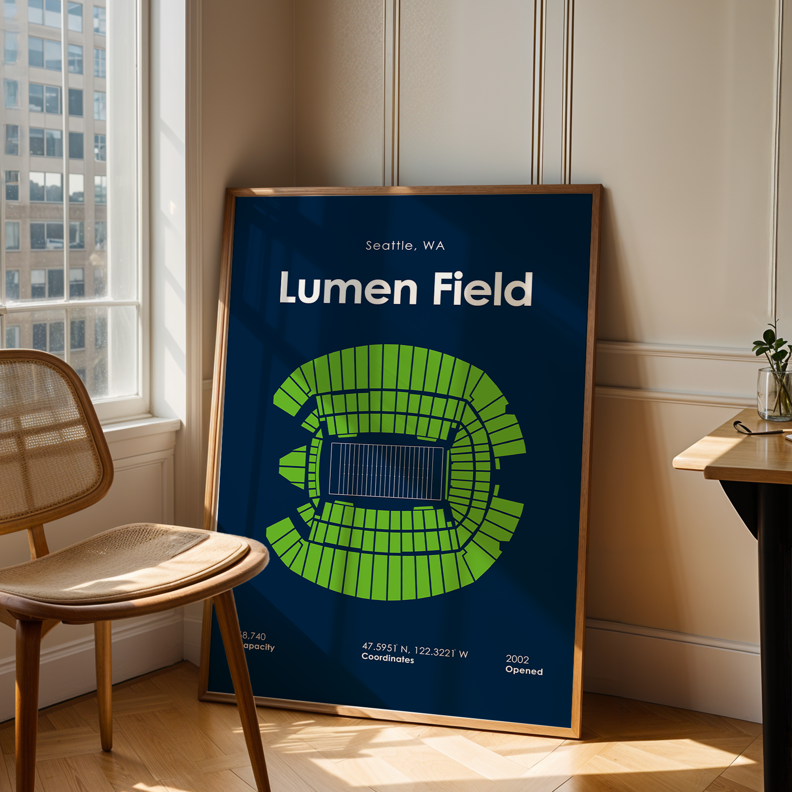 Framed poster of Lumen Field in Seattle, WA, leaning against a wall next to a chair and table.