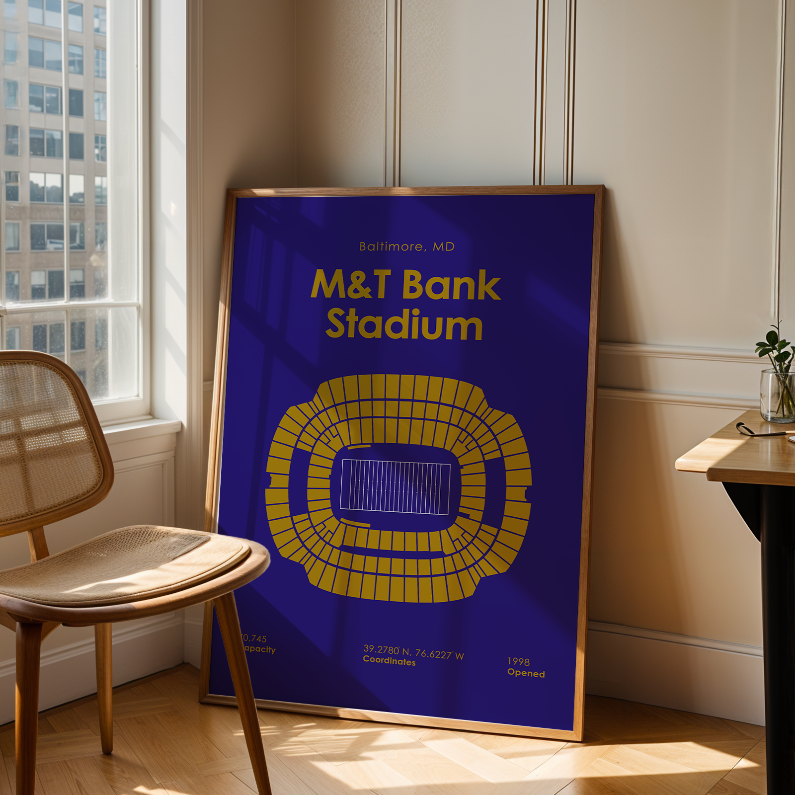 Framed poster of M&T Bank Stadium in a room with a chair and table.