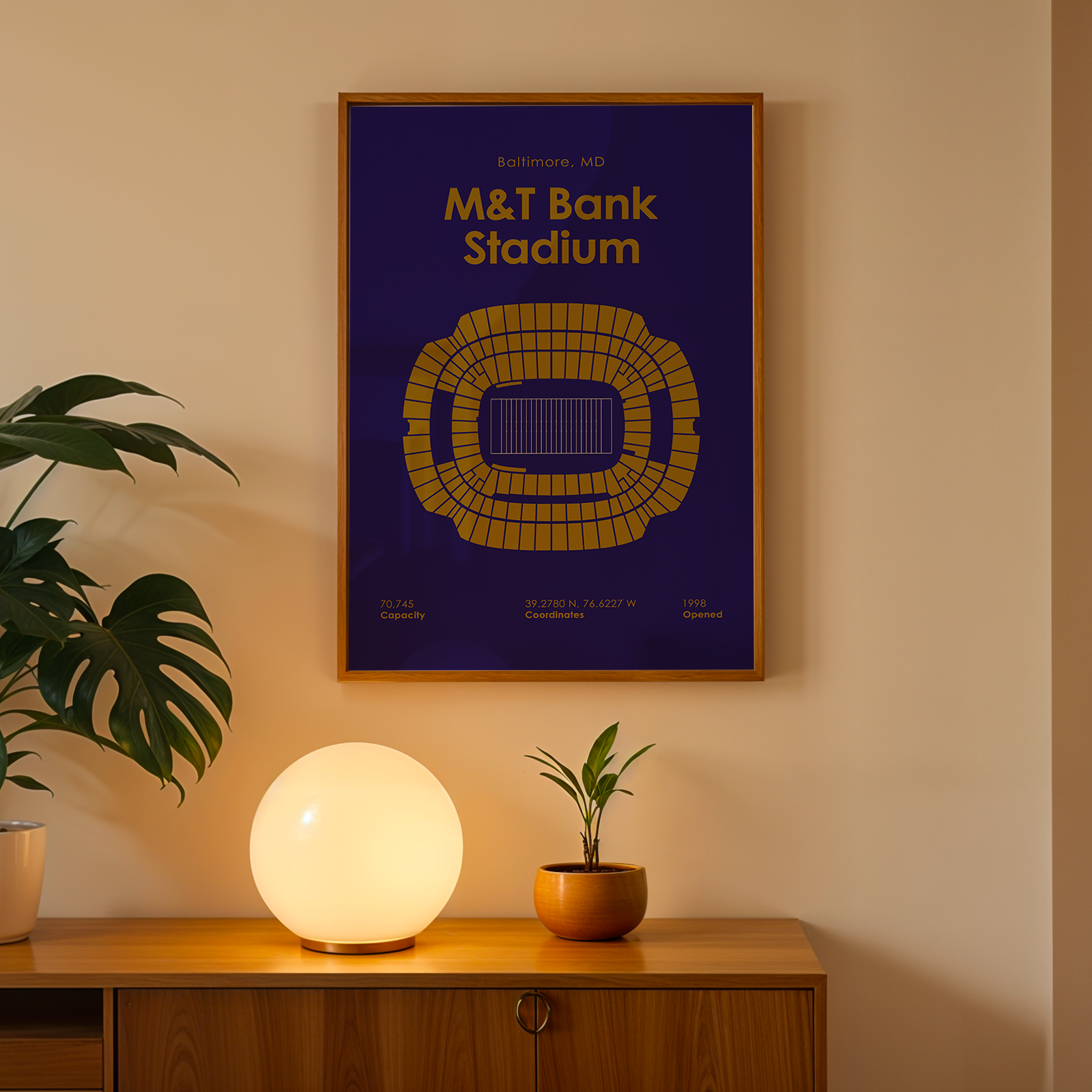 Framed poster of M&T Bank Stadium on a wall above a wooden cabinet with decorative items.