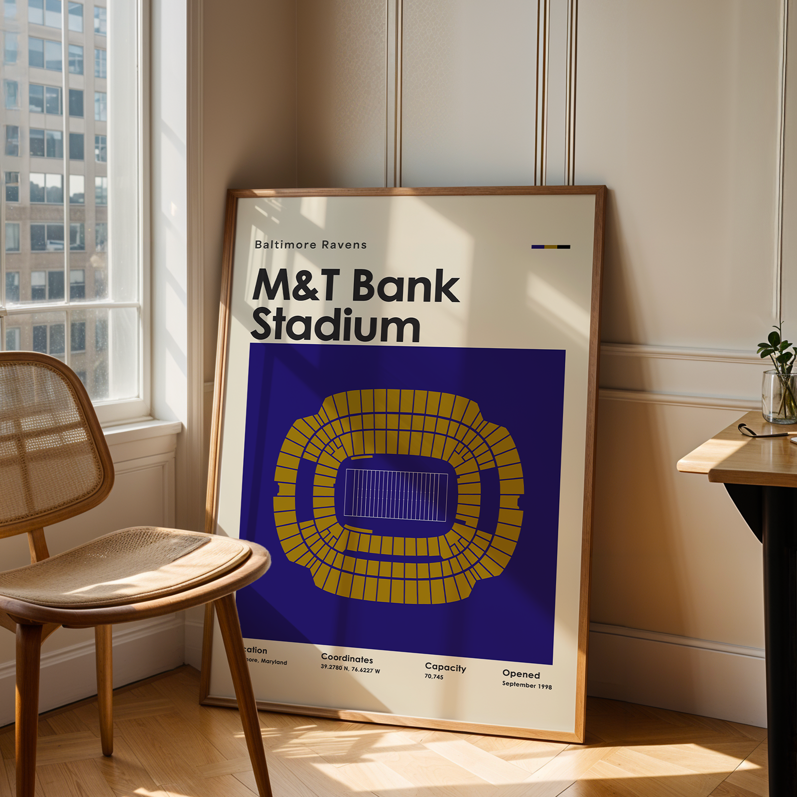Framed poster of M&T Bank Stadium in a room with a window and chair.