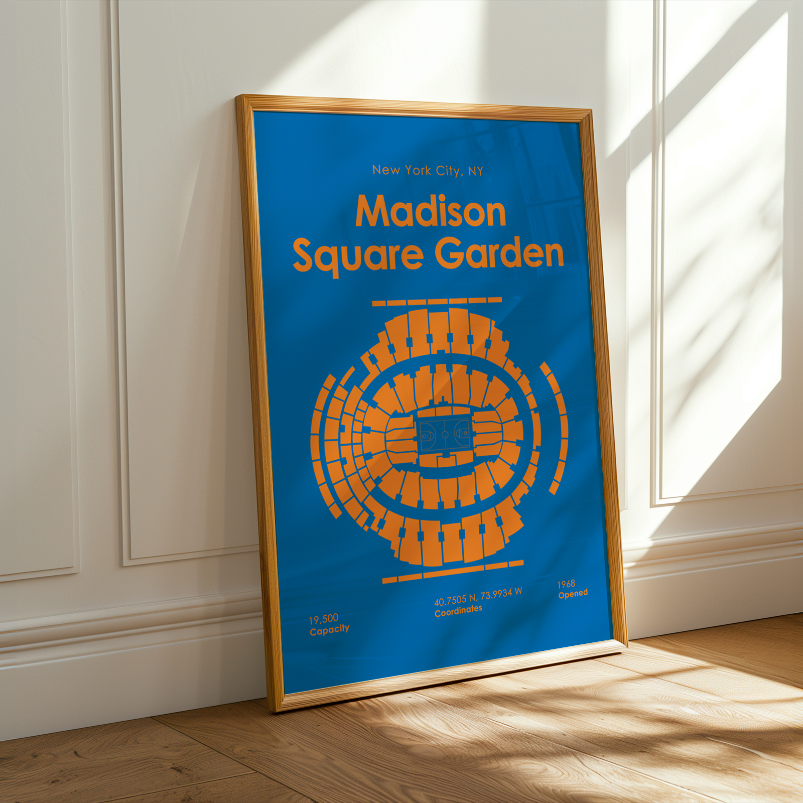 Framed poster of Madison Square Garden with blue background and orange text, leaning against a white wall.