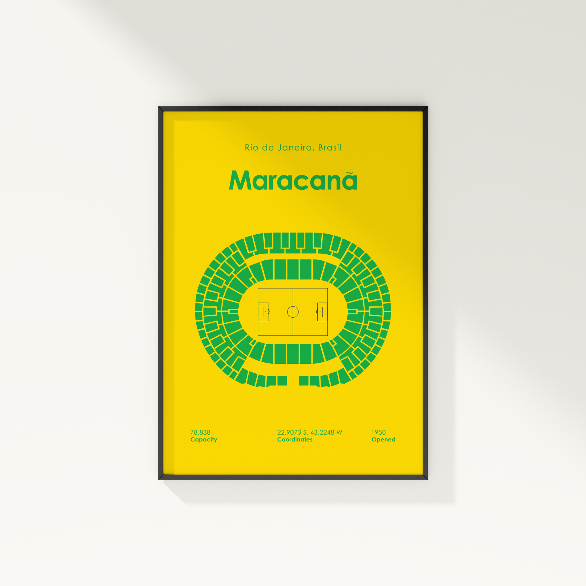 A framed sports poster of the Maracanã stadium in Rio de Janeiro, Brazil, featuring a bright yellow background, green stadium seating diagram, and green text, shown hanging on a white wall.