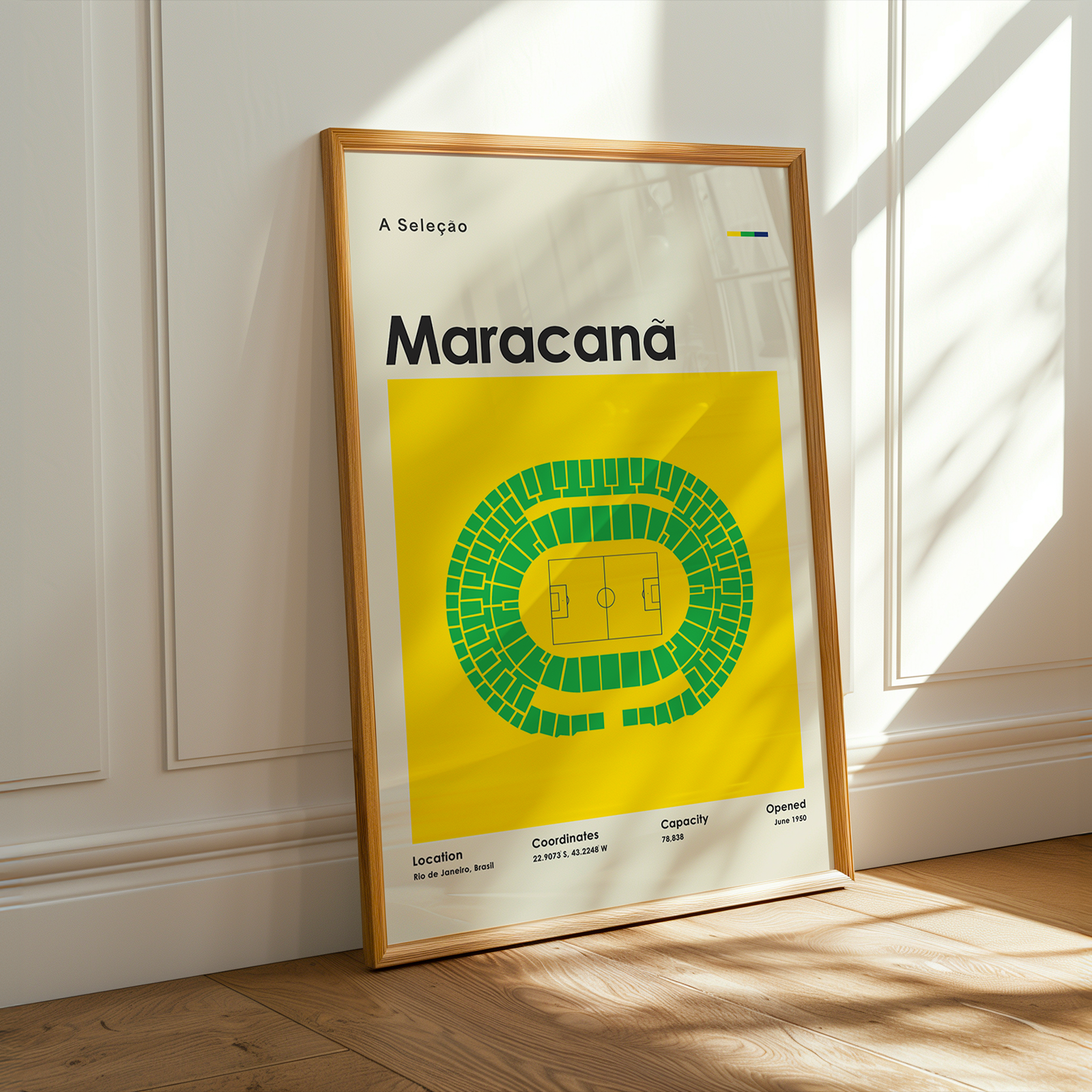 A framed sports poster leaning against a white paneled wall on a wooden floor, with warm sunlight casting shadows across the scene. The poster features a bright yellow background, green stadium seating illustration, and the word 'Maracana' in bold black text.