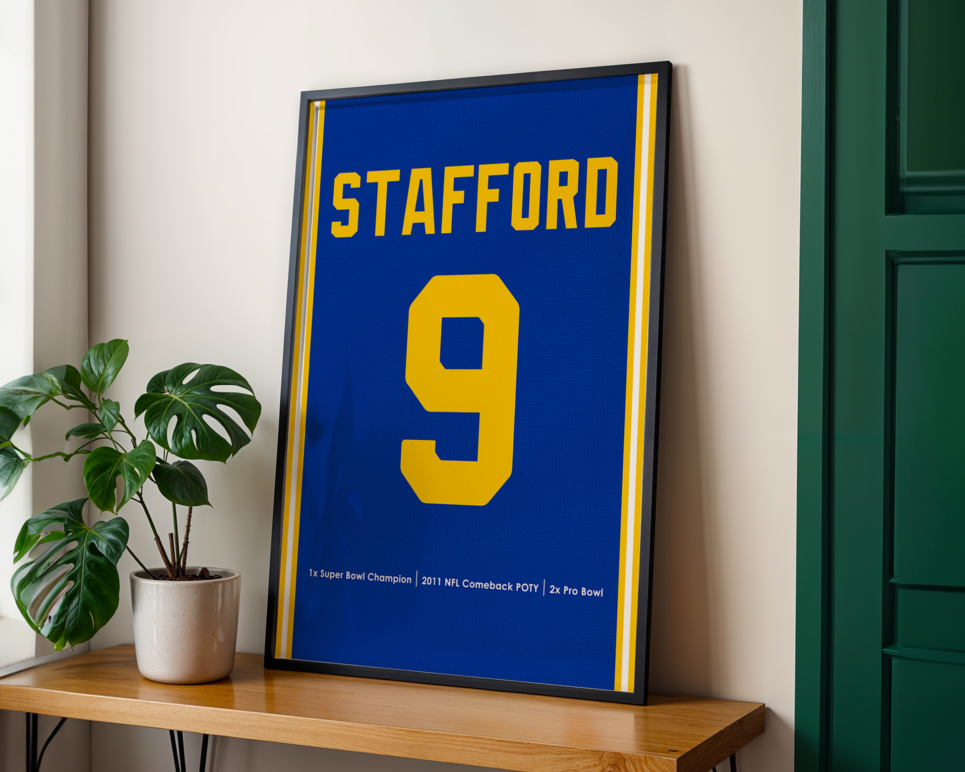 Framed sports jersey with 'Stafford' and number '9' on a wooden shelf.