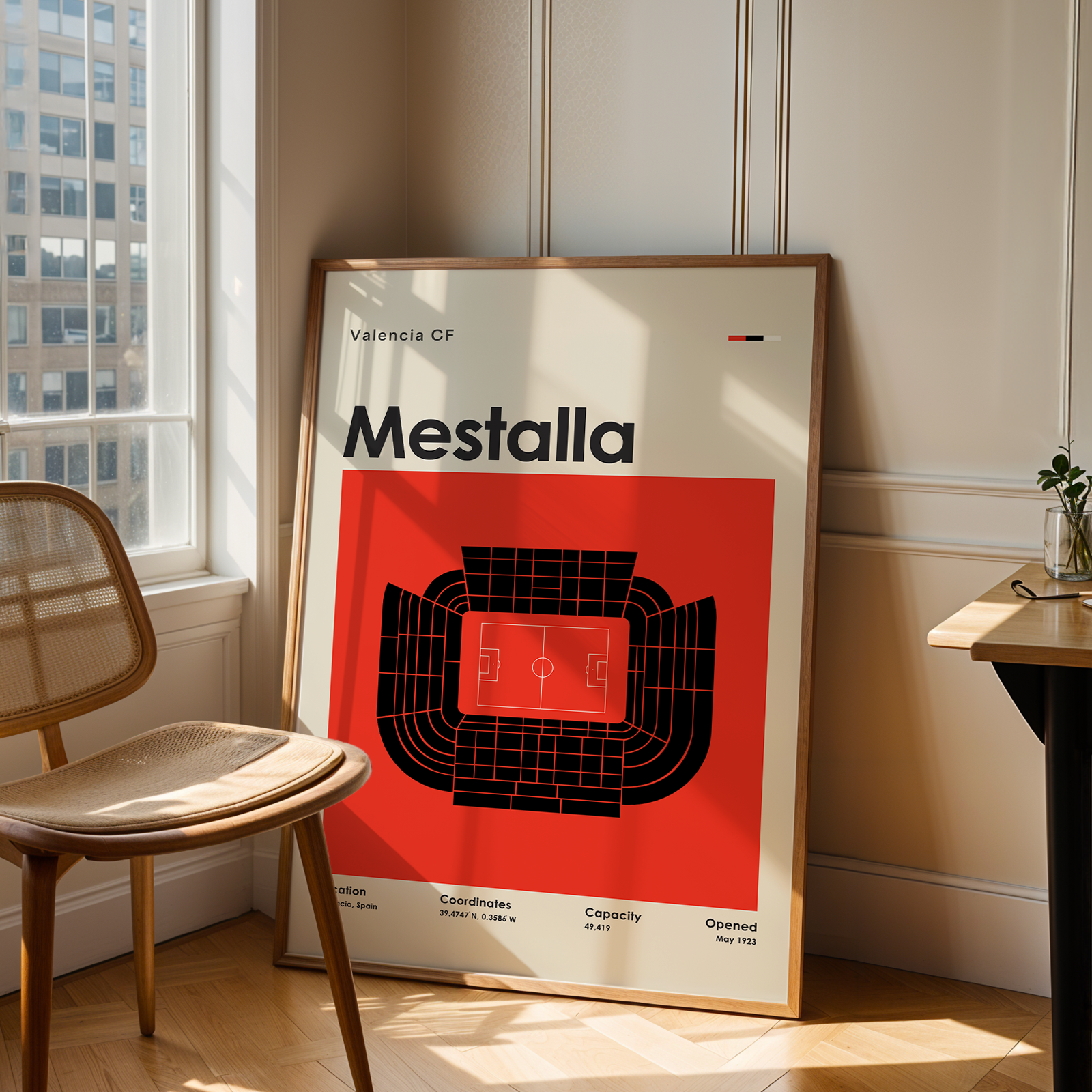 Poster of Valencia CF Mestalla stadium in a room with a chair and table.